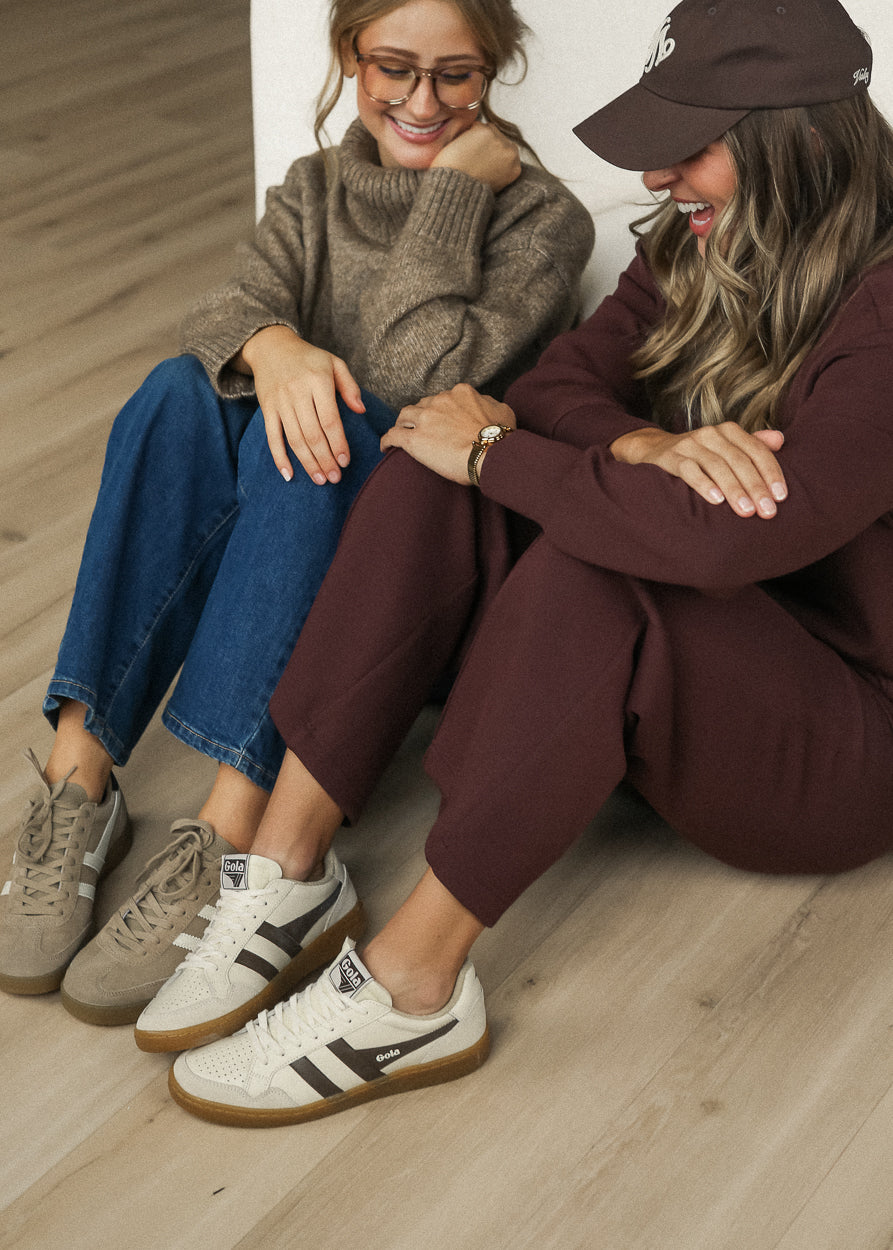 Ivory and brown Gola Eagle '86 sneakers styled with a burgundy lounge set in a casual indoor setting.