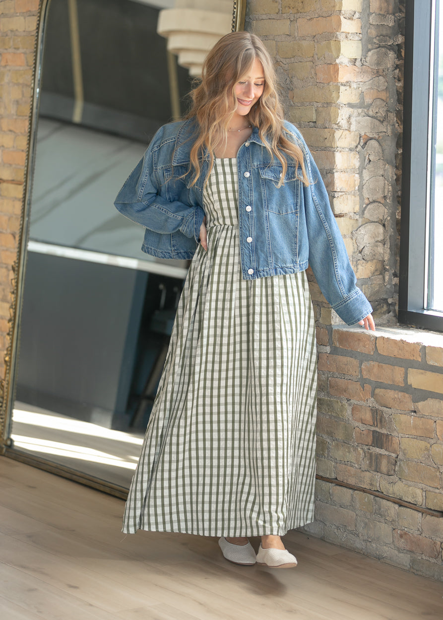 Gingham maxi dress styled with a denim jacket and woven flats.