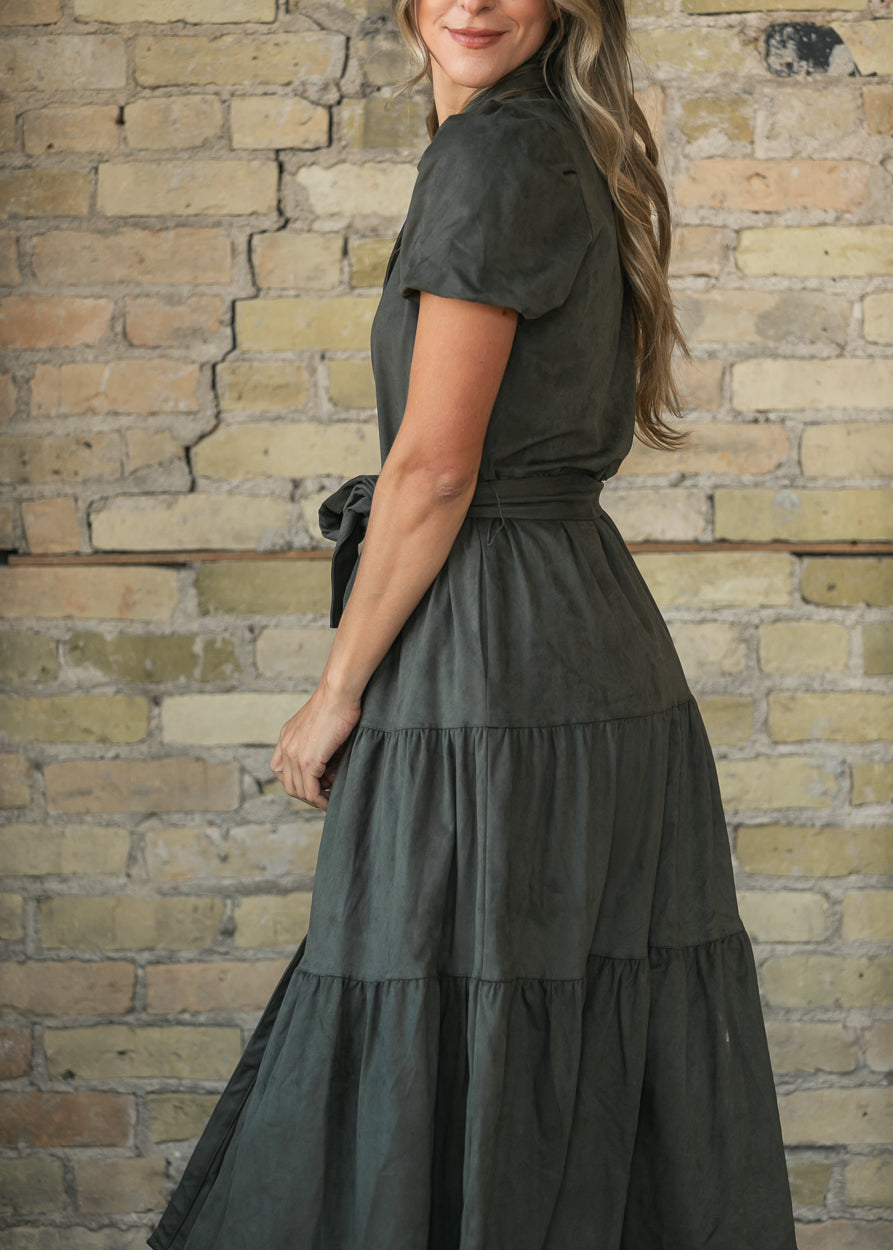 Side view of olive suede midi dress showing side pocket, tiered skirt, and mid-calf length.