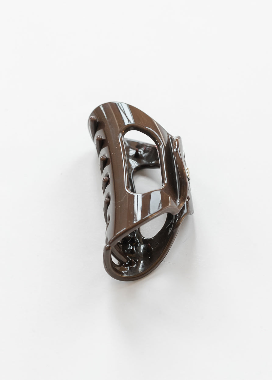 Glossy espresso claw clip angled to show its curved shape, spring closure, and open center.