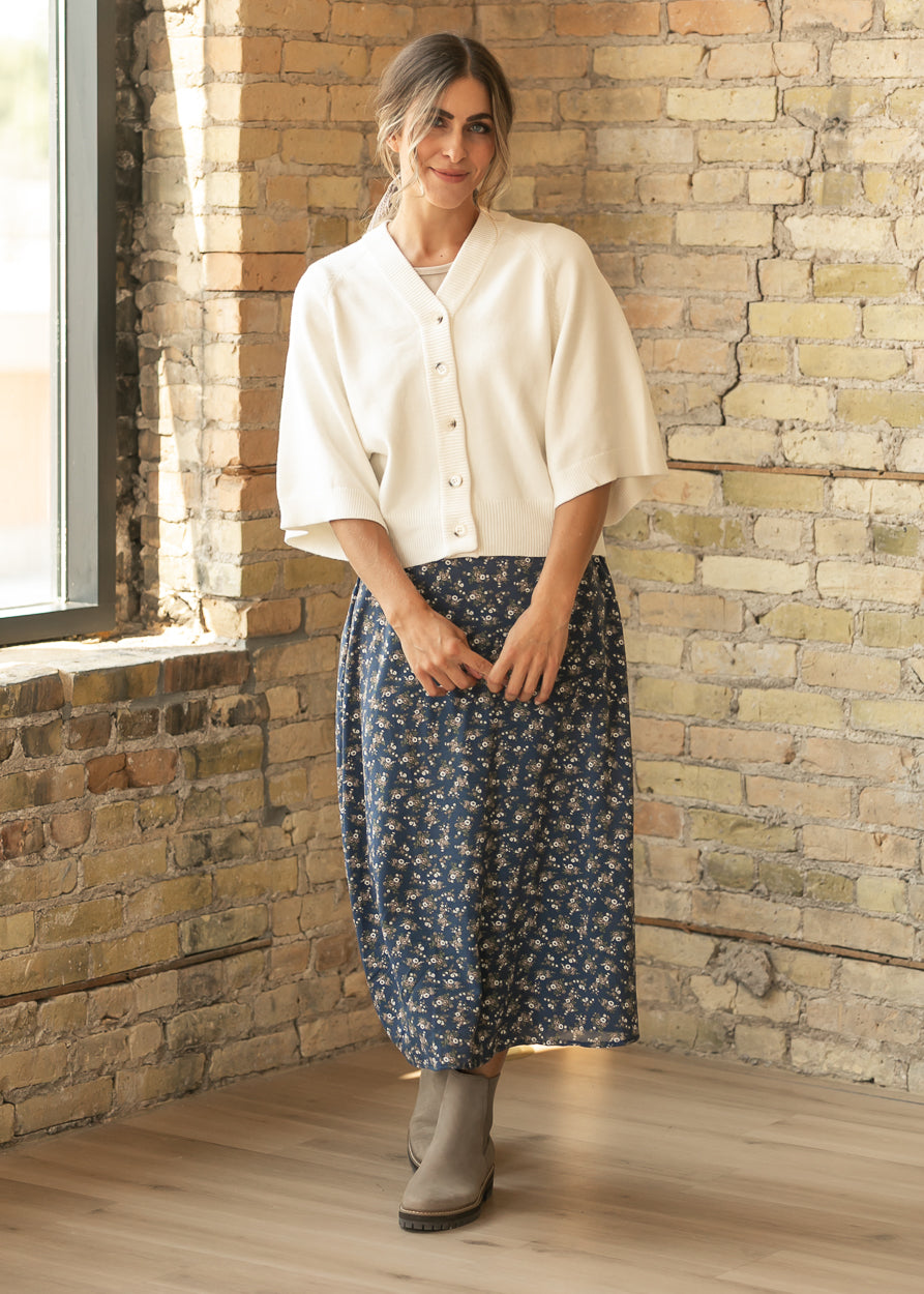 Cream V neck cardigan styled with a navy floral maxi skirt and taupe ankle boots.