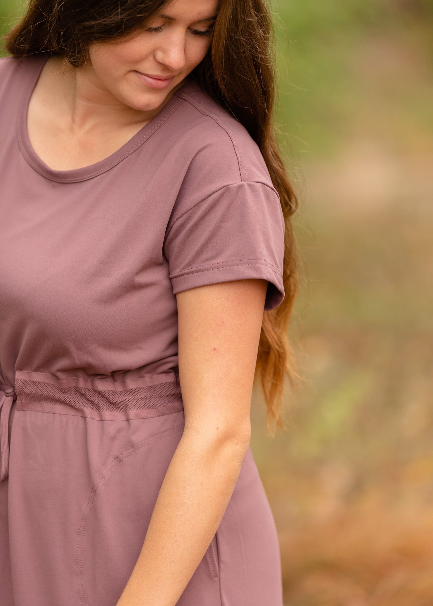 This is a Cinch Waist Athletic midi dress in a purpley taupe color that has a mesh detail and large side pockets.