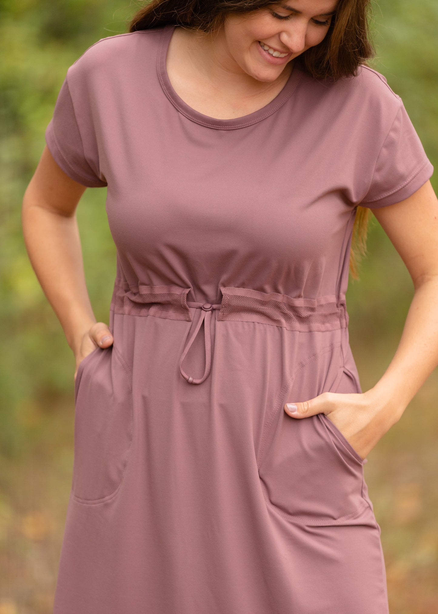 This is a Cinch Waist Athletic midi dress in a purpley taupe color that has a mesh detail and large side pockets.