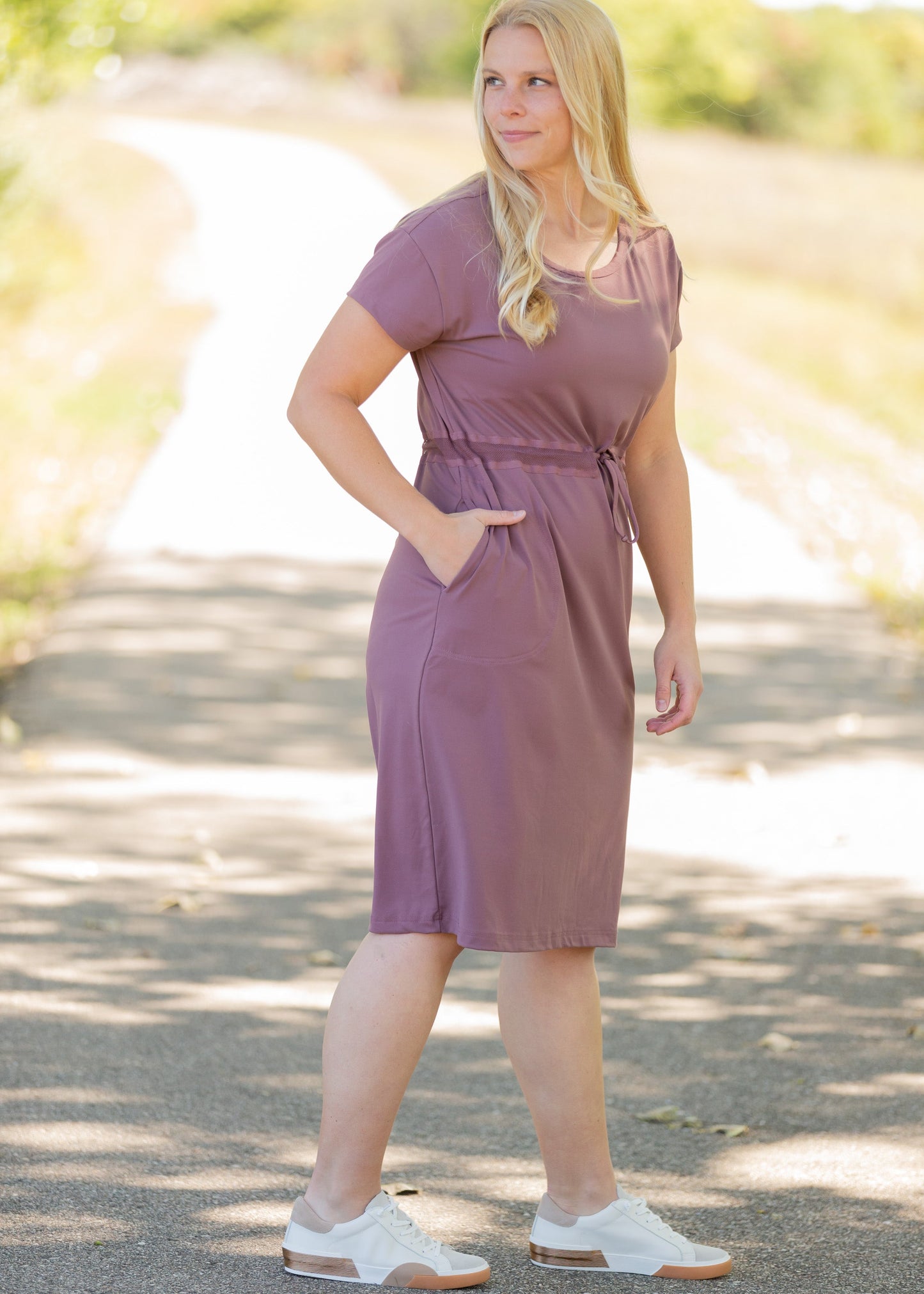 This is a Cinch Waist Athletic midi dress in a purpley taupe color that has a mesh detail and large side pockets.