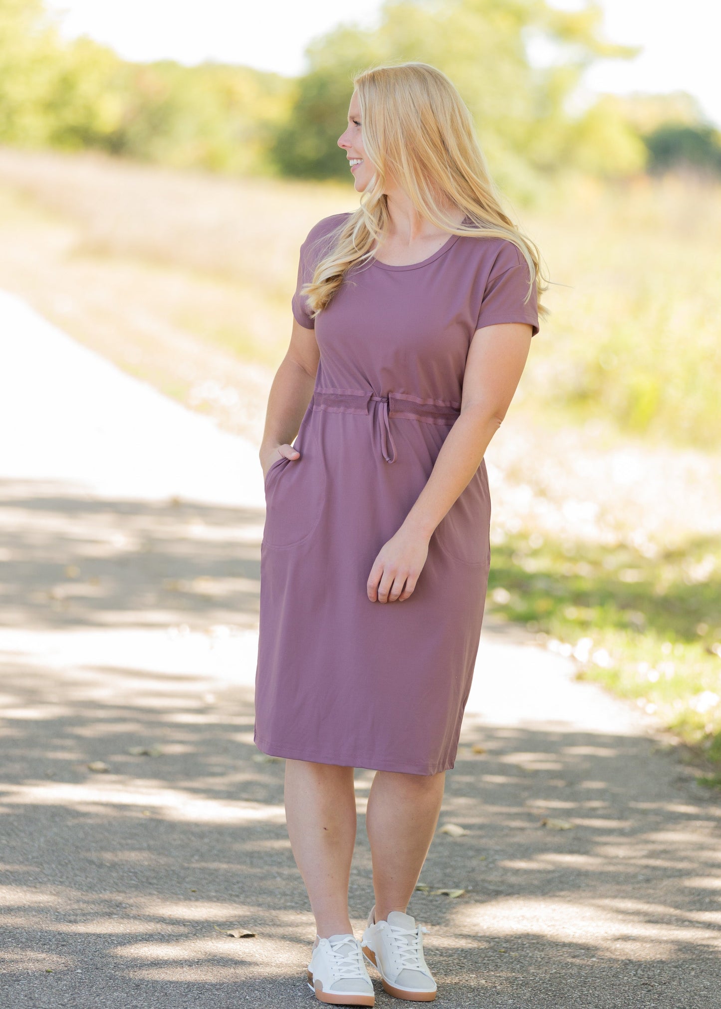 This is a Cinch Waist Athletic midi dress in a purpley taupe color that has a mesh detail and large side pockets.