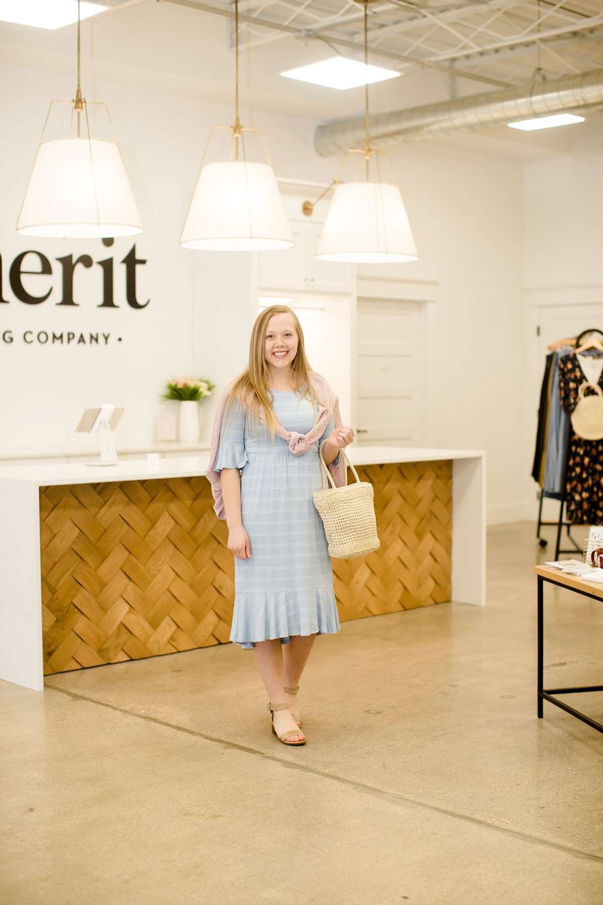 Woman wearing a modest baby blue and white striped midi dress with ruffles on the hem and sleeves