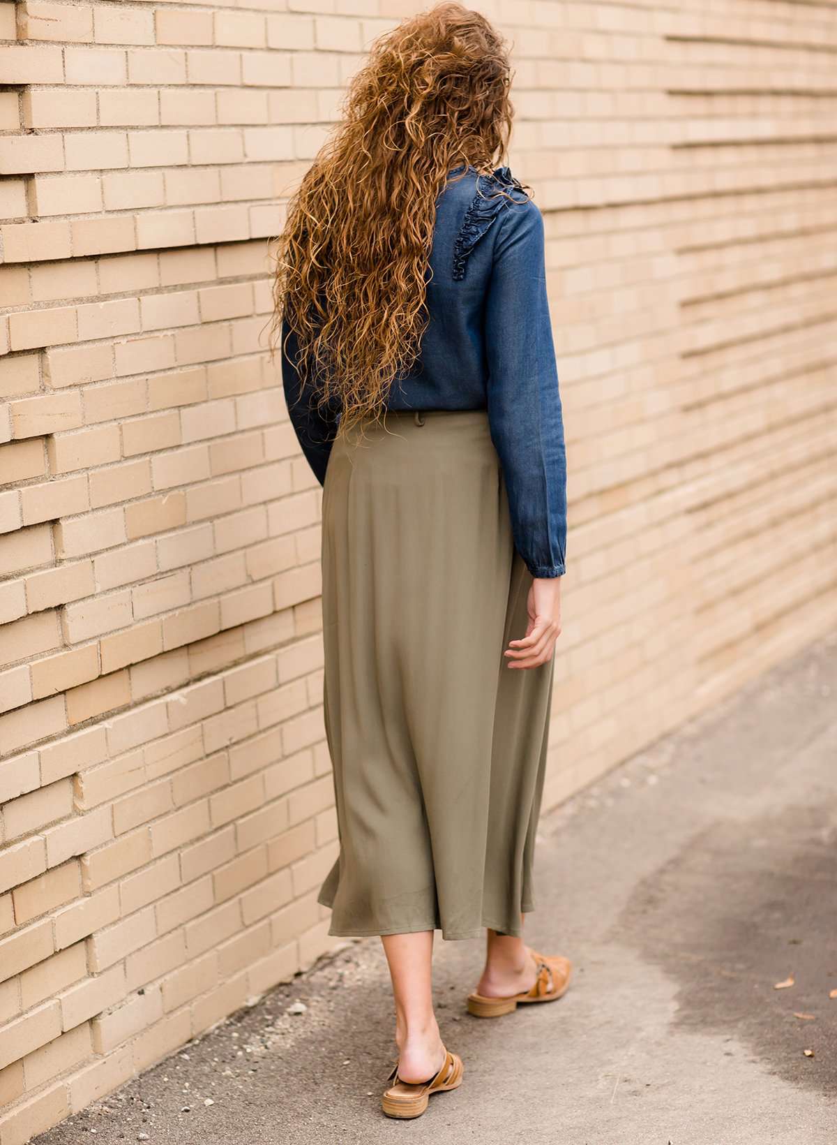 Woman wearing a lightweight ankle-length olive skirt with buttons up the front.
