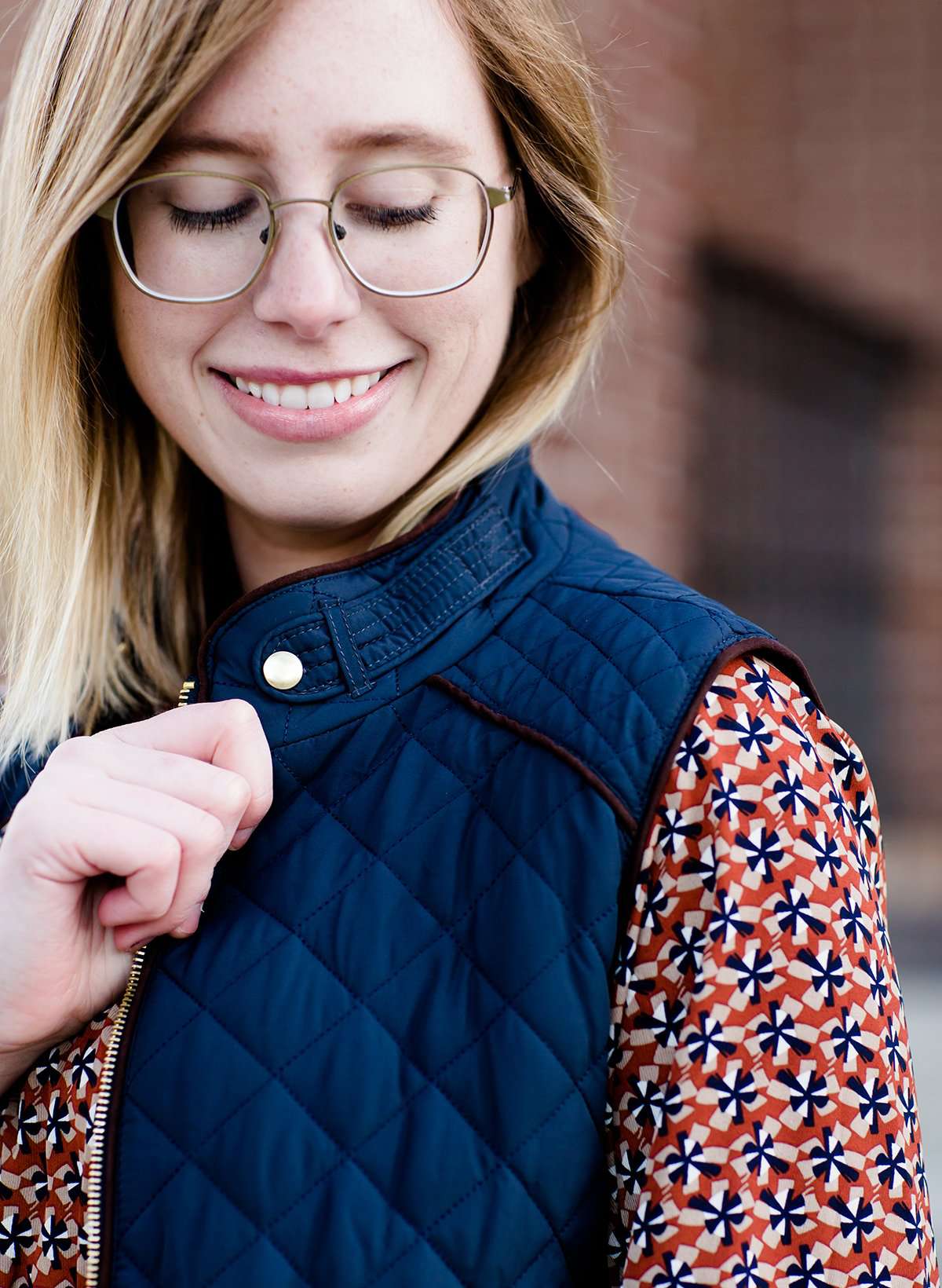 Woman wearing a cold weather, quilted puffer vest. This vest comes in mauve, black, navy and wine. It features pockets and a front zip.