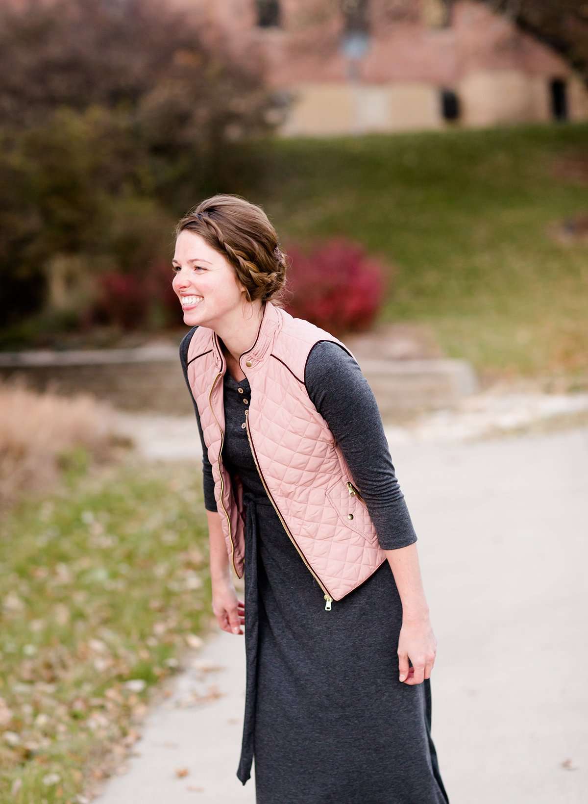 Woman wearing a cold weather, quilted puffer vest. This vest comes in mauve, black, navy and wine. It features pockets and a front zip.