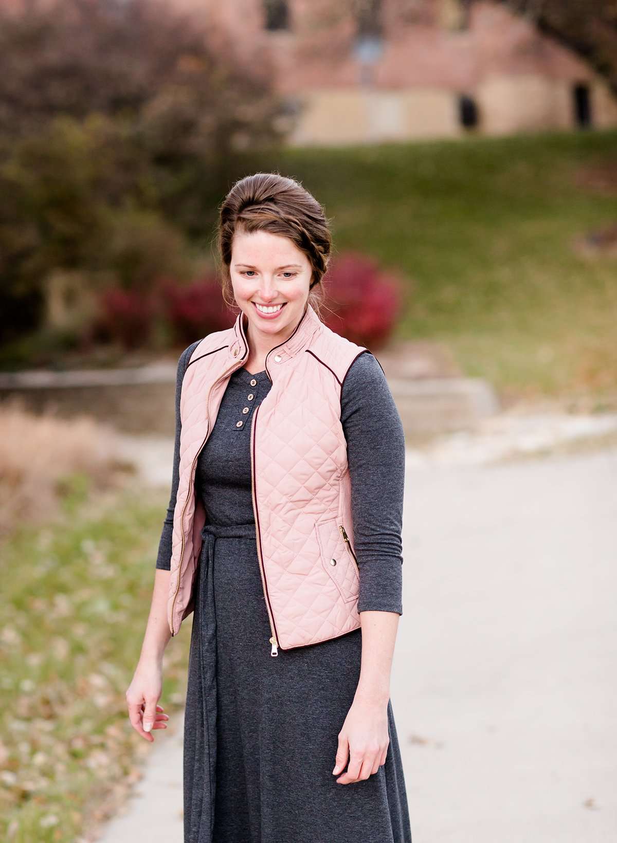 Woman wearing a cold weather, quilted puffer vest. This vest comes in mauve, black, navy and wine. It features pockets and a front zip.