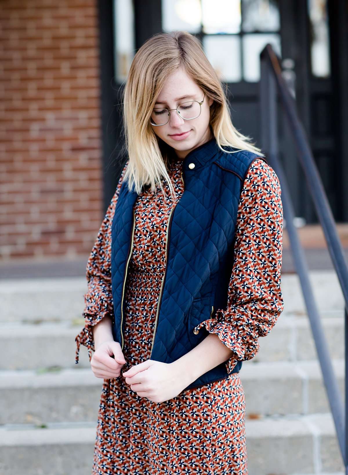 Woman wearing a cold weather, quilted puffer vest. This vest comes in mauve, black, navy and wine. It features pockets and a front zip.