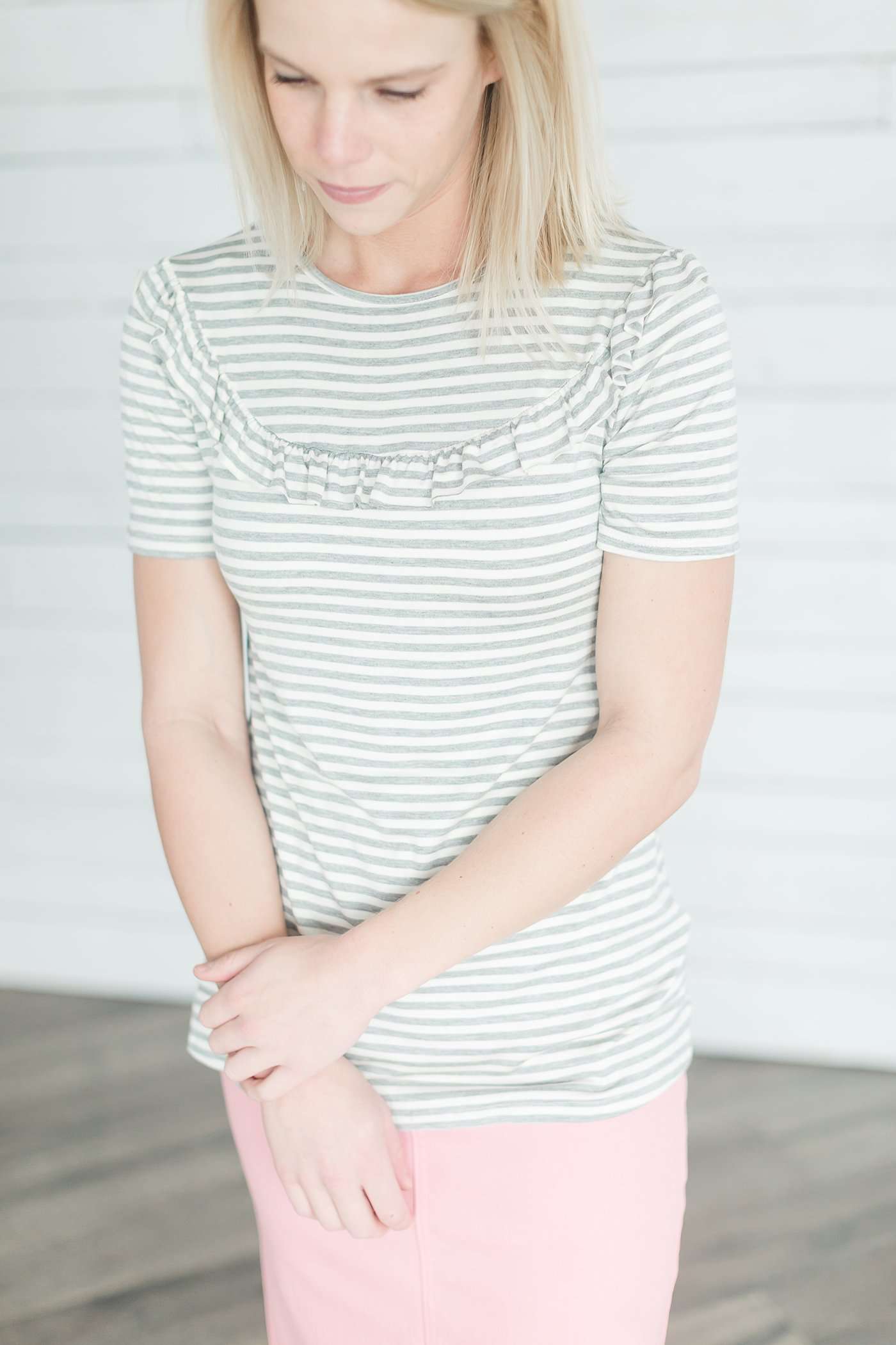 Grey and white striped crew neck tee shirt with a ruffle just above the chest.