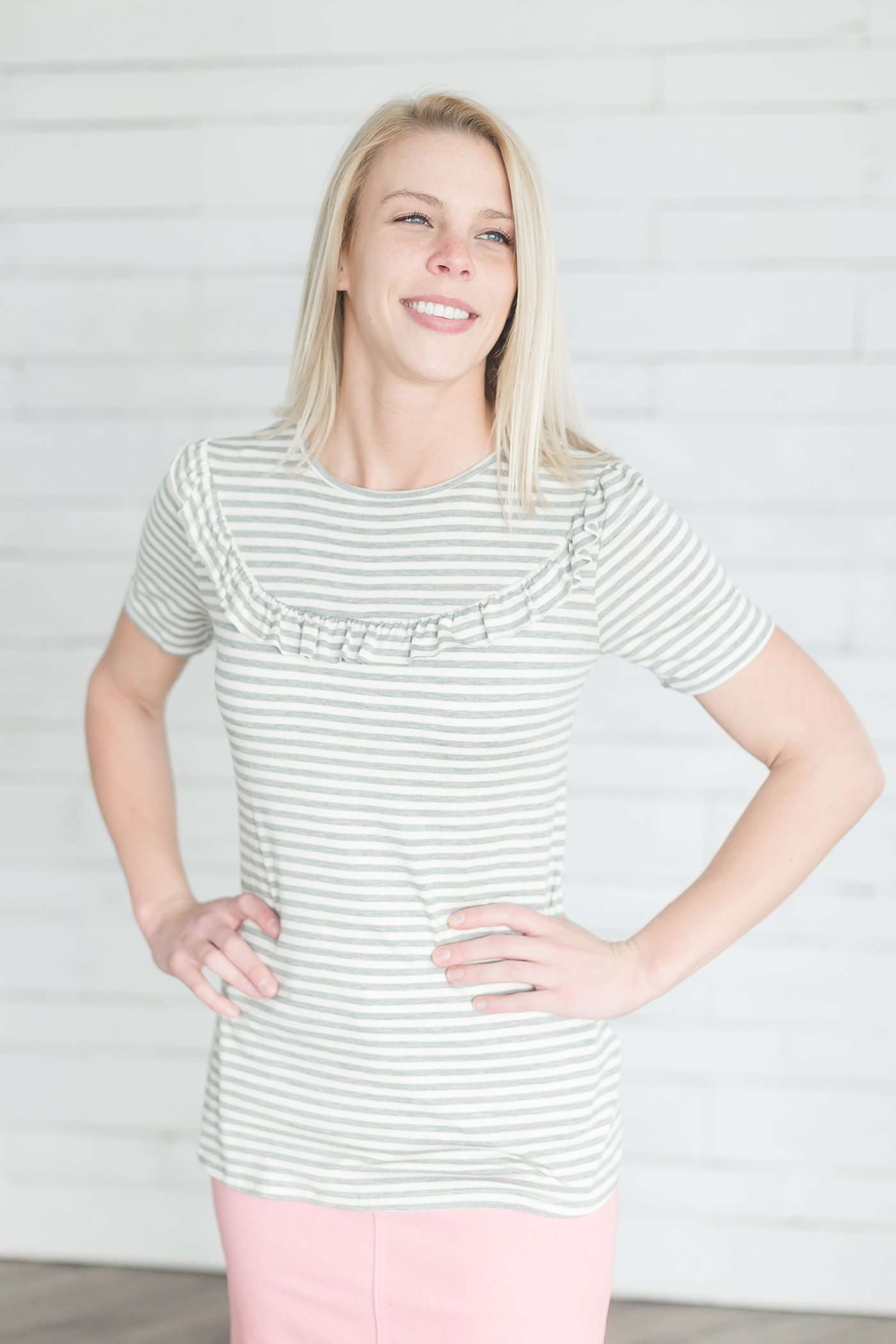 Grey and white striped crew neck tee shirt with a ruffle just above the chest.