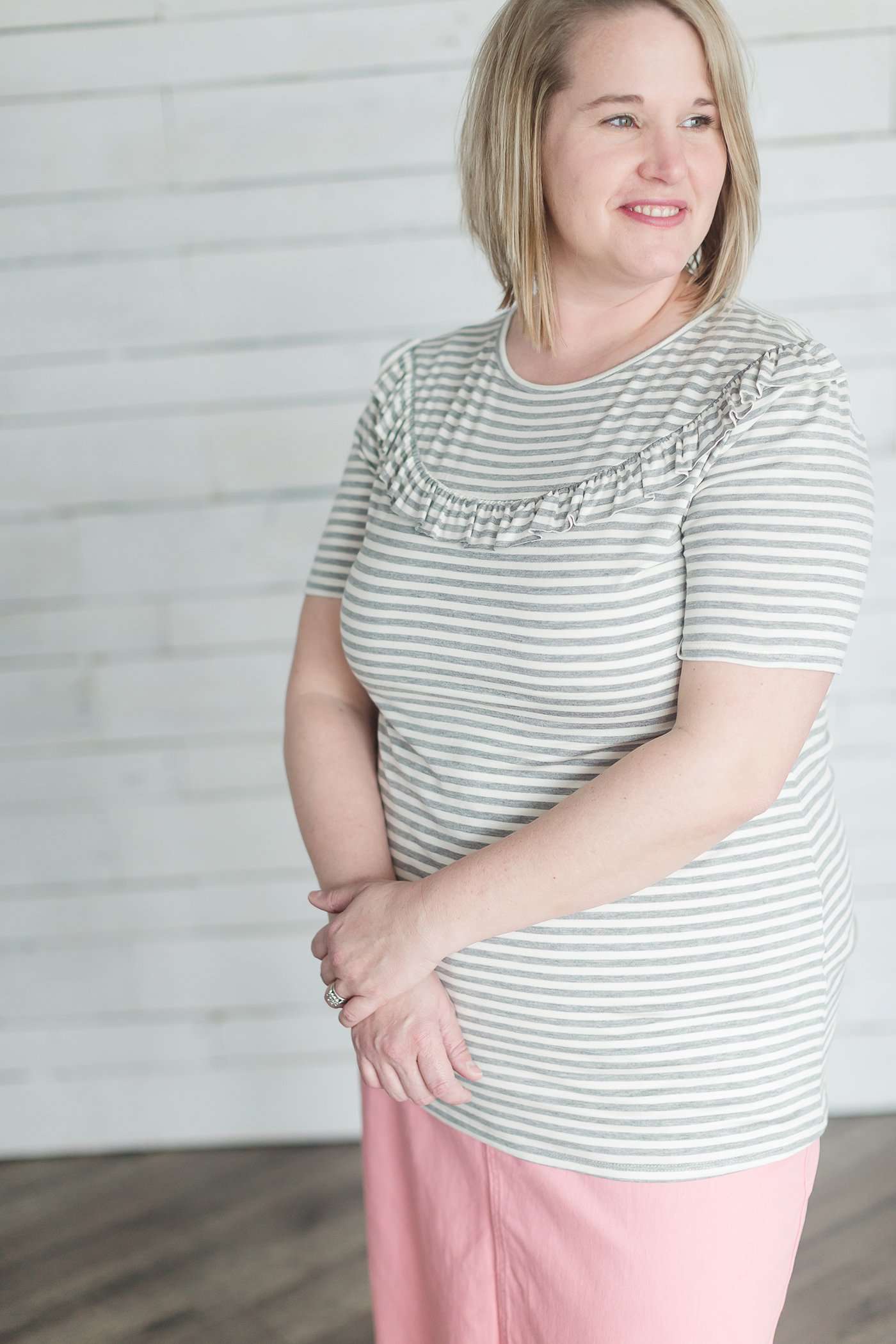 Grey and white striped crew neck tee shirt with a ruffle just above the chest.