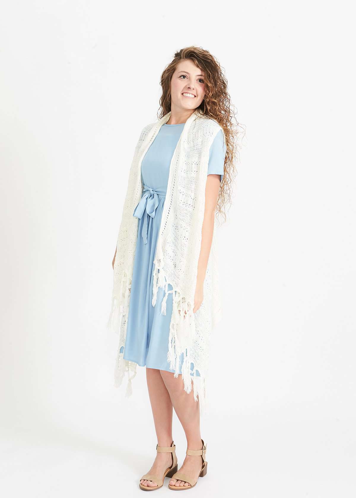 Woman wearing a cream fringed knit vest with a crochet look