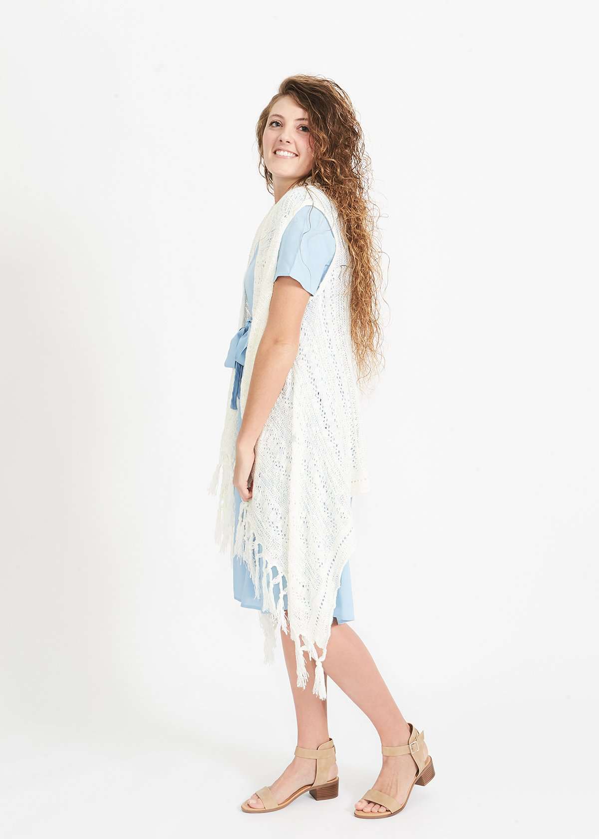 Woman wearing a cream fringed knit vest with a crochet look