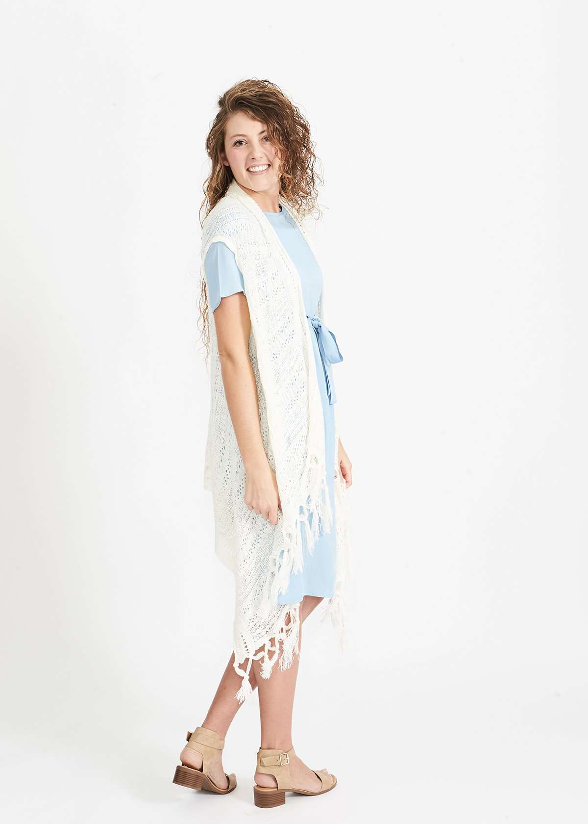 Woman wearing a cream fringed knit vest with a crochet look