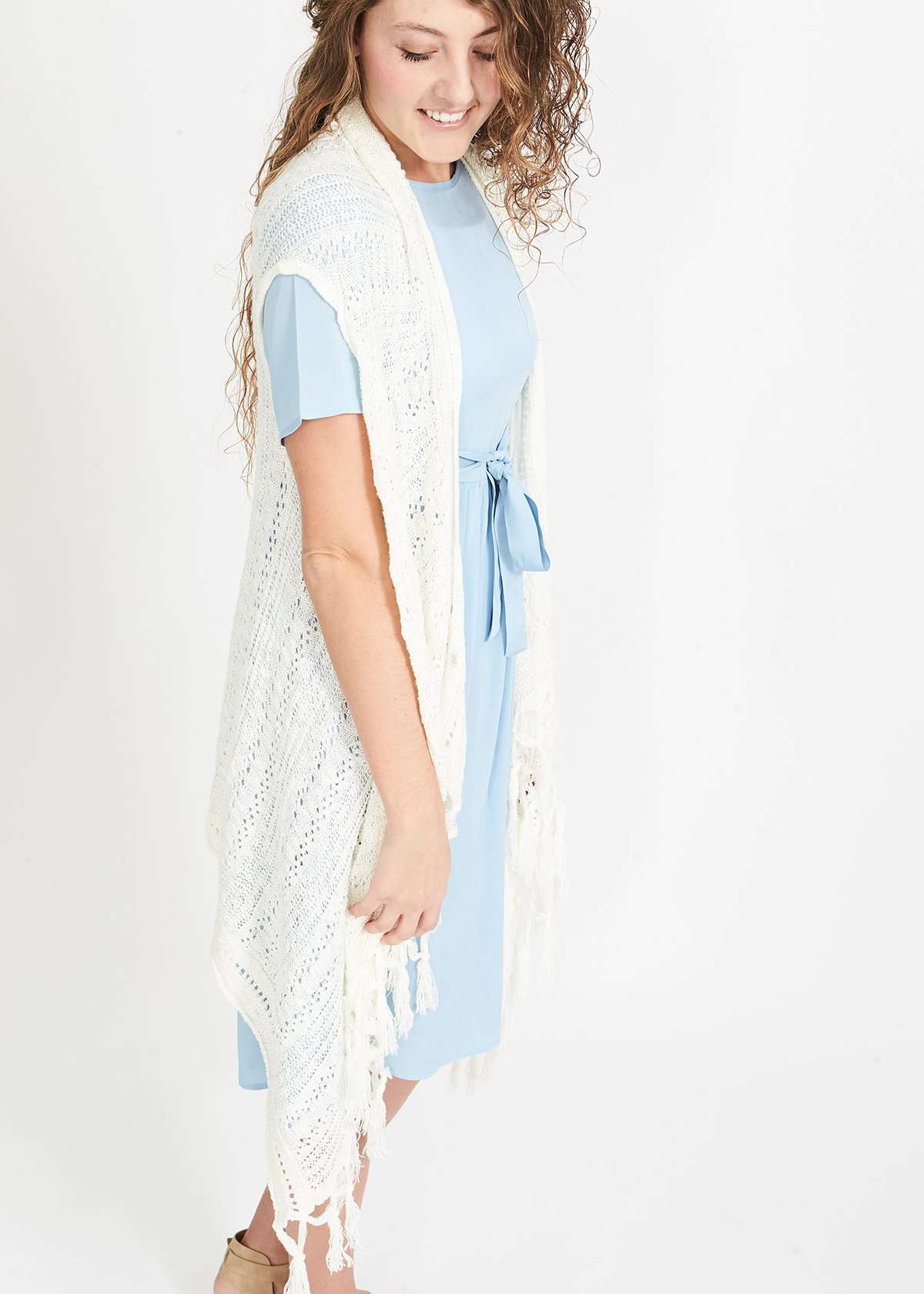 Woman wearing a cream fringed knit vest with a crochet look
