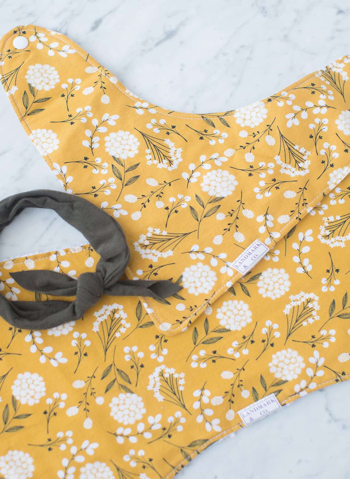 This is a mustard colored baby burp cloth, baby bandana and headband gift set.