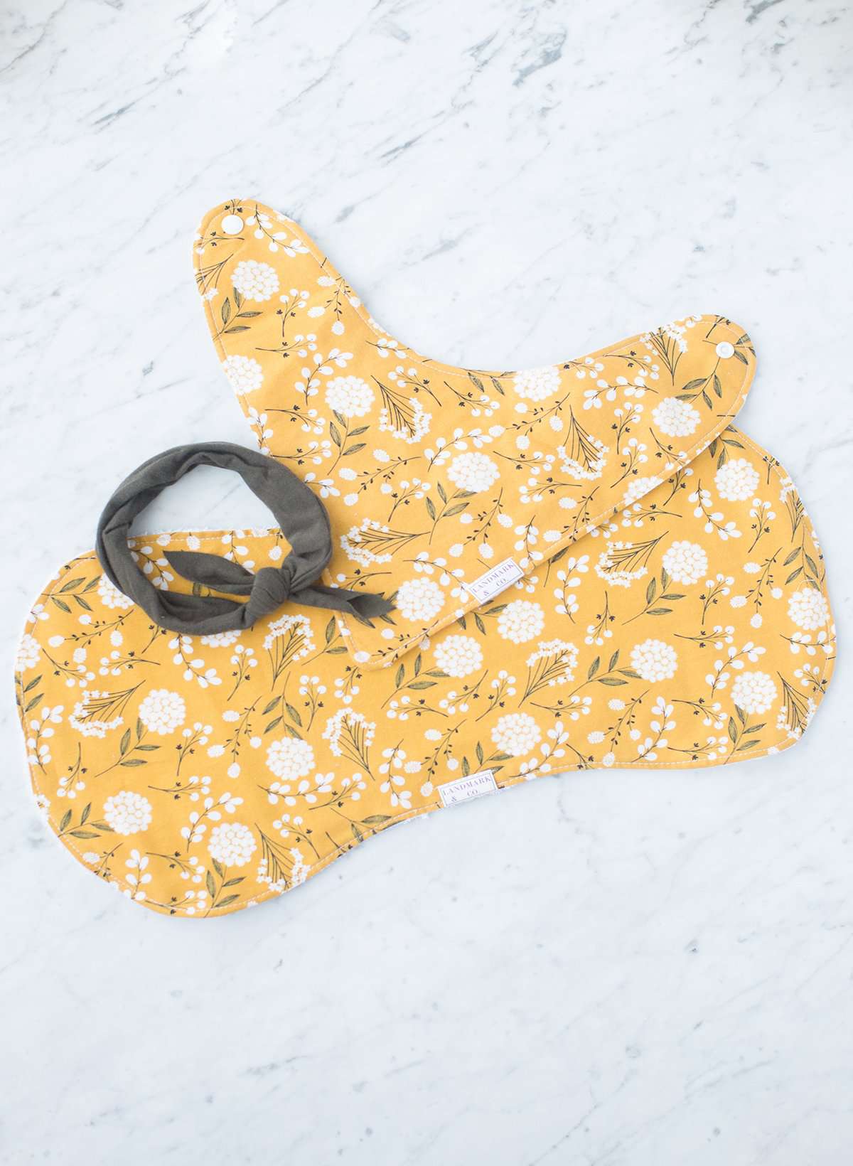 This is a mustard colored baby burp cloth, baby bandana and headband gift set.