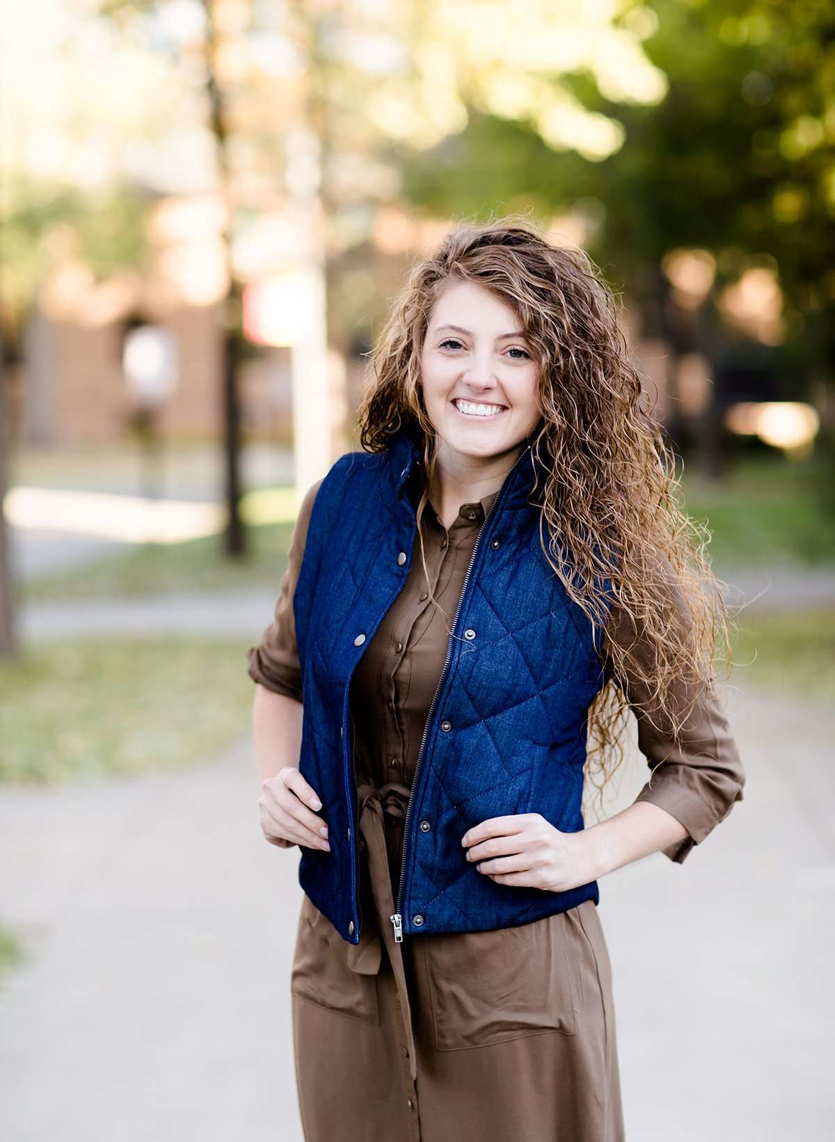 Woman wearing a denim quilted modest vest with a plaid and flannel lining.