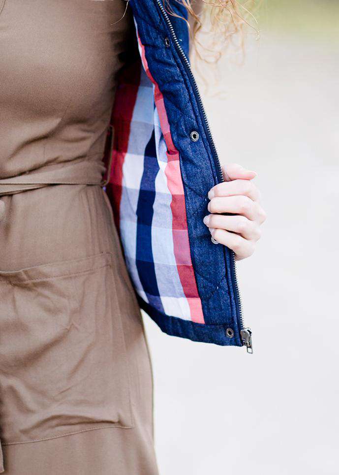 Woman wearing a denim quilted modest vest with a plaid and flannel lining.