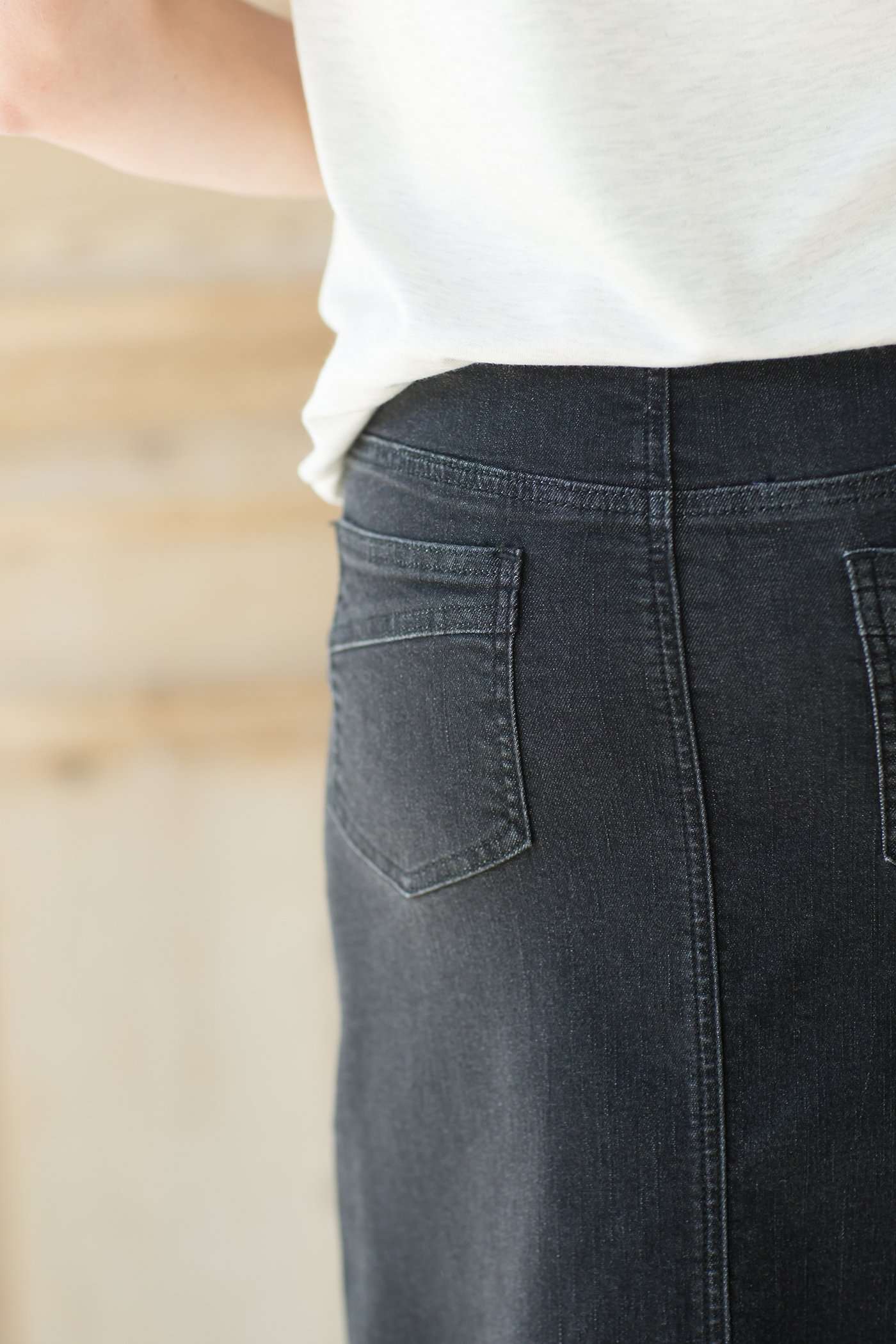 Woman wearing a modest long black denim skirt with pockets