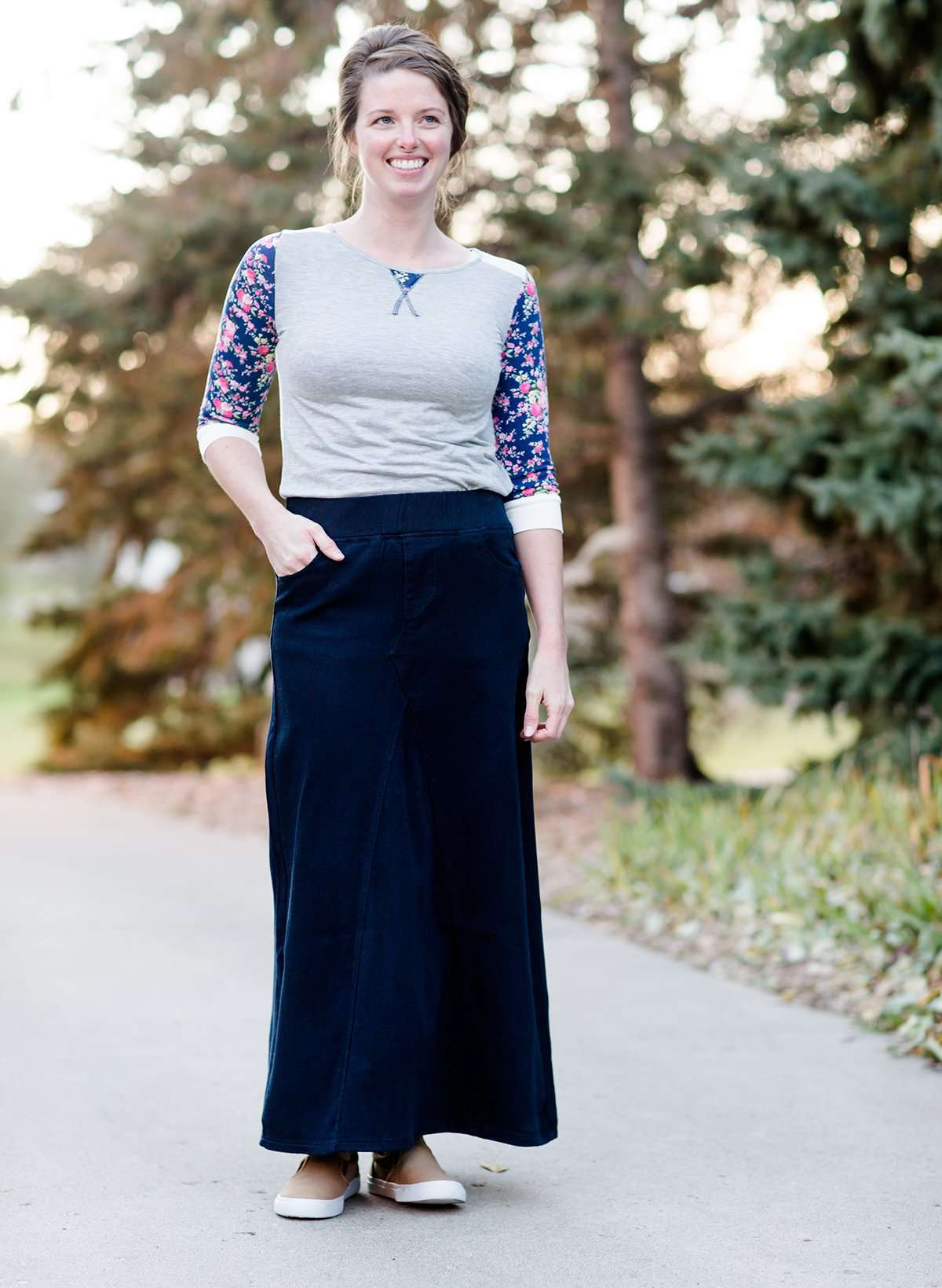 Women wearing a long dark blue denim skirt that is a-line and has flare. This modest skirt is also paired with a floral and gray raglan tee.