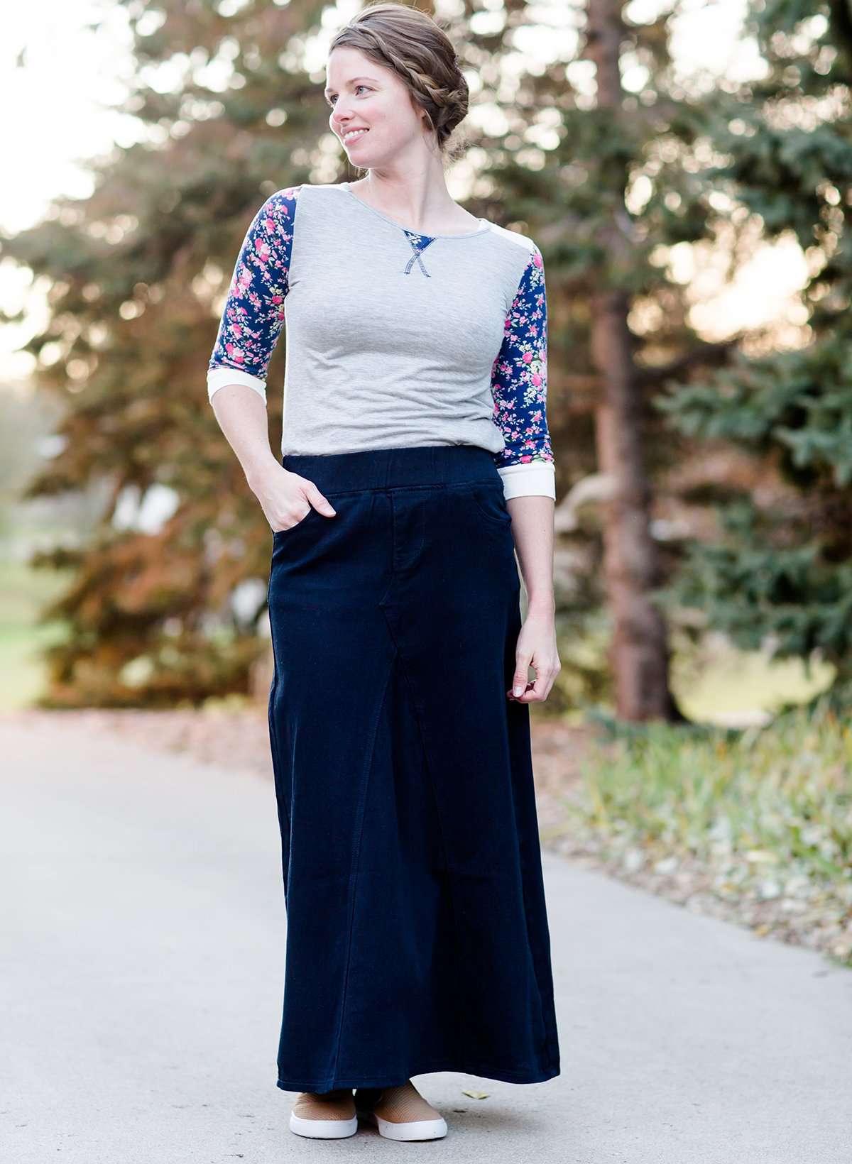 Women wearing a long dark blue denim skirt that is a-line and has flare. This modest skirt is also paired with a floral and gray raglan tee.