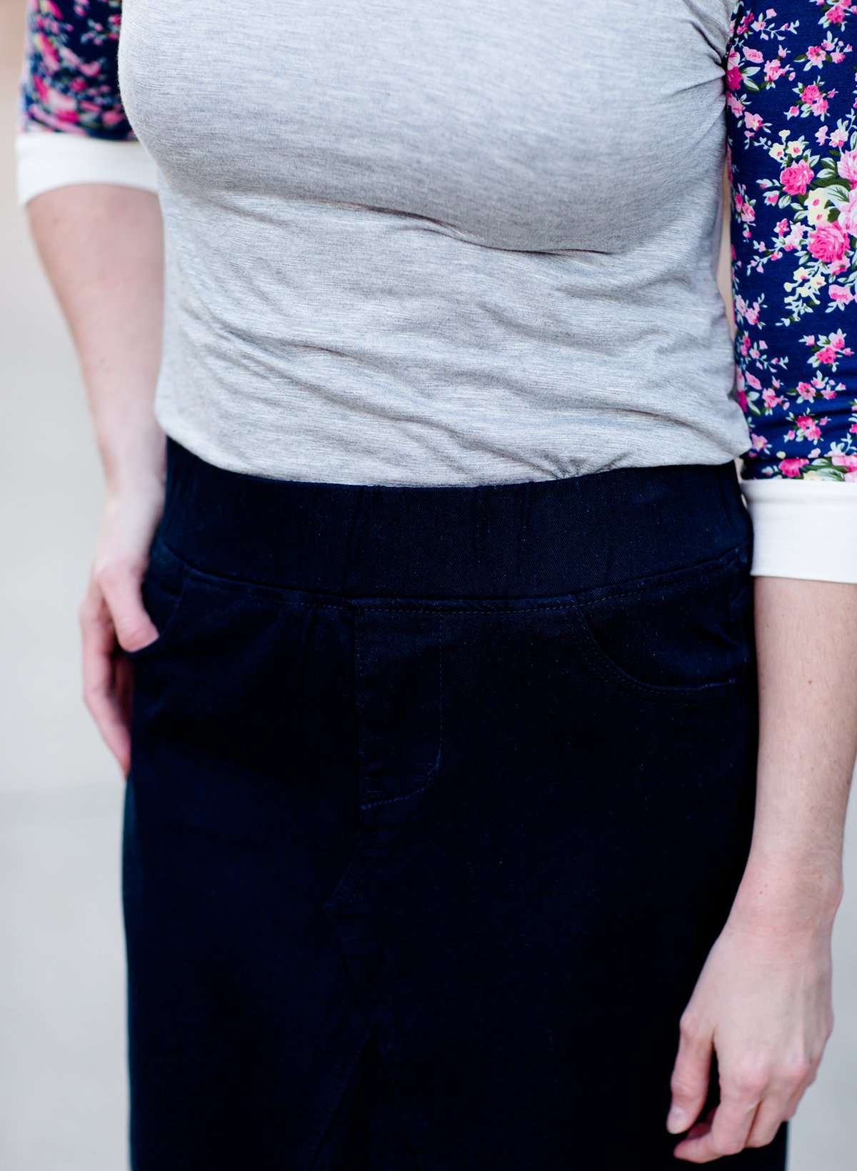 Women wearing a long dark blue denim skirt that is a-line and has flare. This modest skirt is also paired with a floral and gray raglan tee.