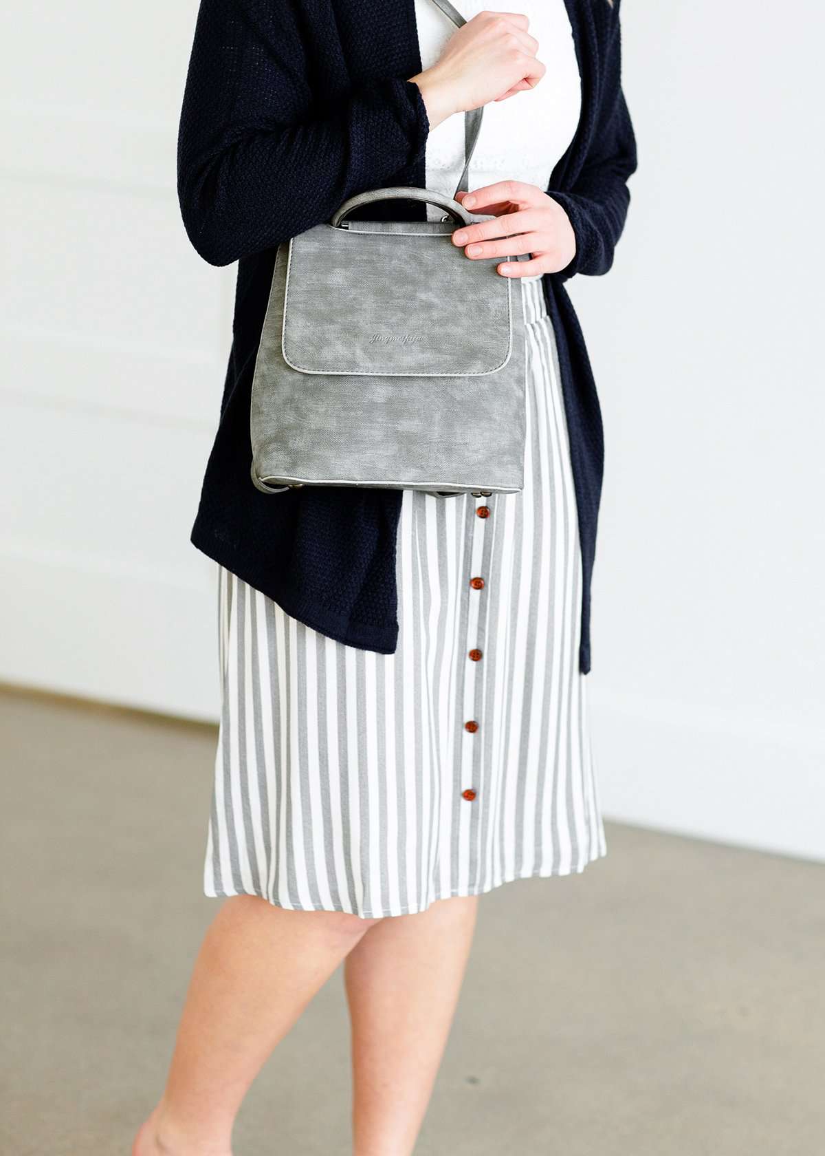 Woman wearing a gray striped skirt with camel colored faux buttons on the front that also has an elastic waistband