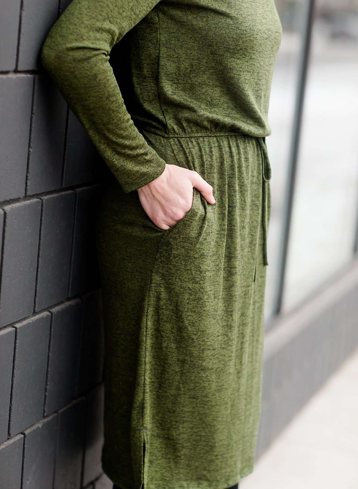 Woman wearing a olive colored hacci midi dress with a elastic waist and paired with black sole society boots