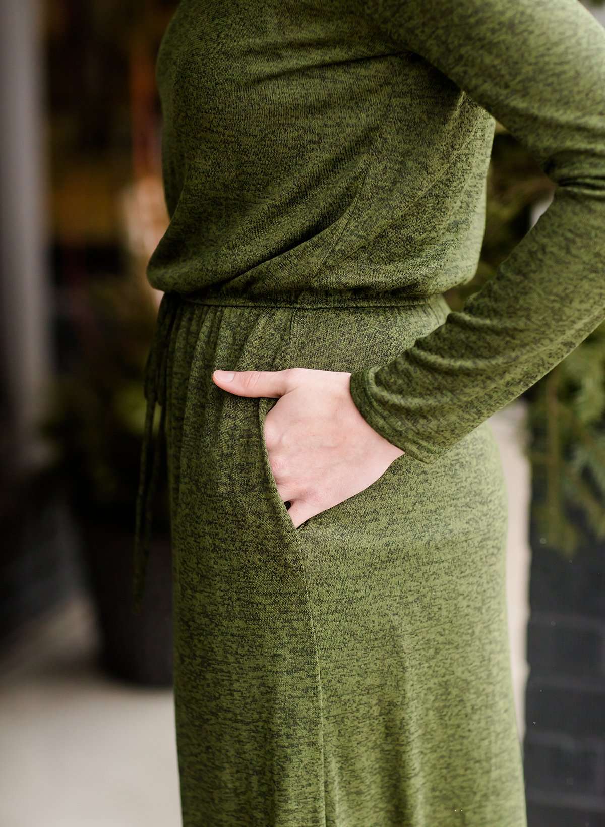 Woman wearing a olive colored hacci midi dress with a elastic waist and paired with black sole society boots