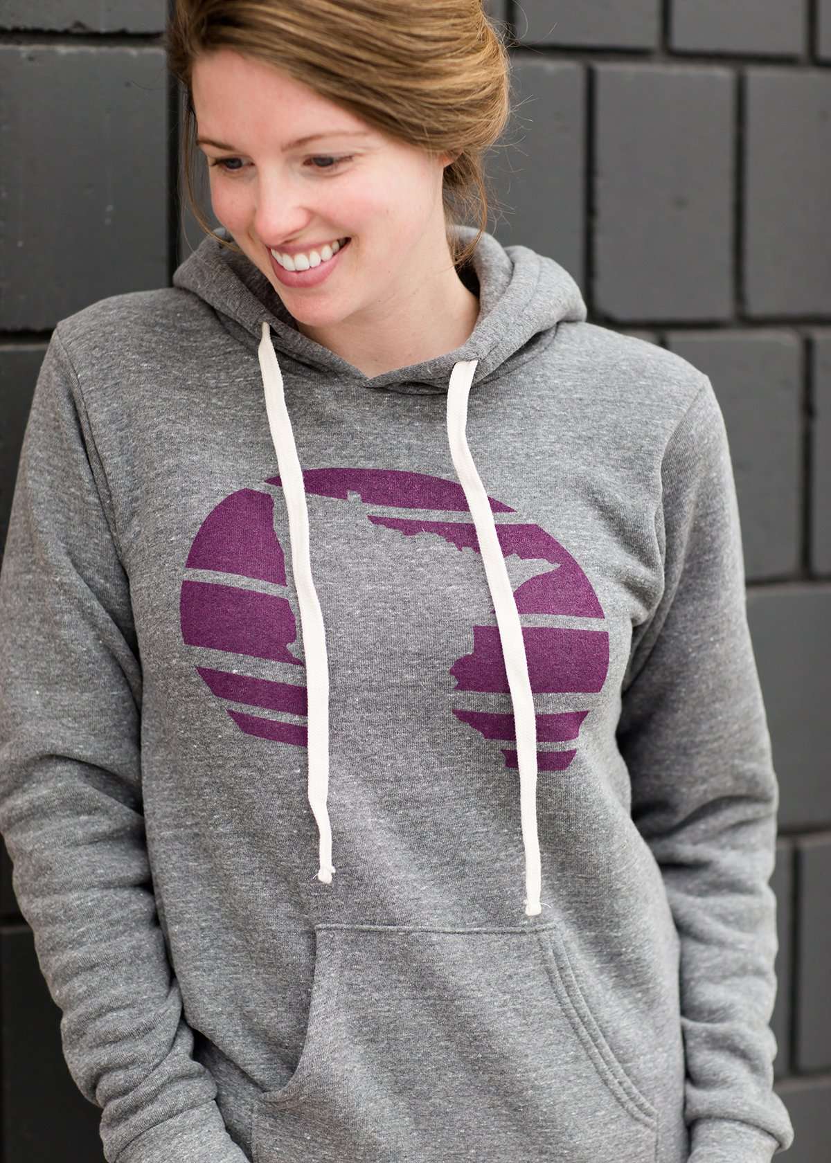Triblend Minnesota hoodie on a young woman, the hoodie is navy with a gold MN emblem on front and gray with a purple MN emblem on front.