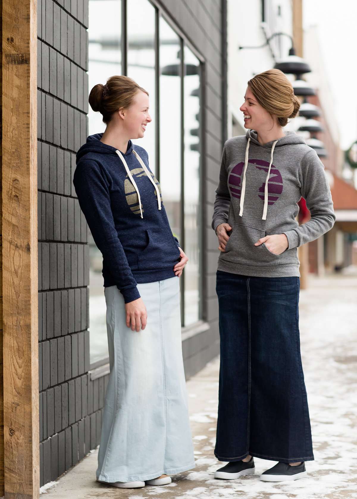 Triblend Minnesota hoodie on a young woman, the hoodie is navy with a gold MN emblem on front and gray with a purple MN emblem on front.