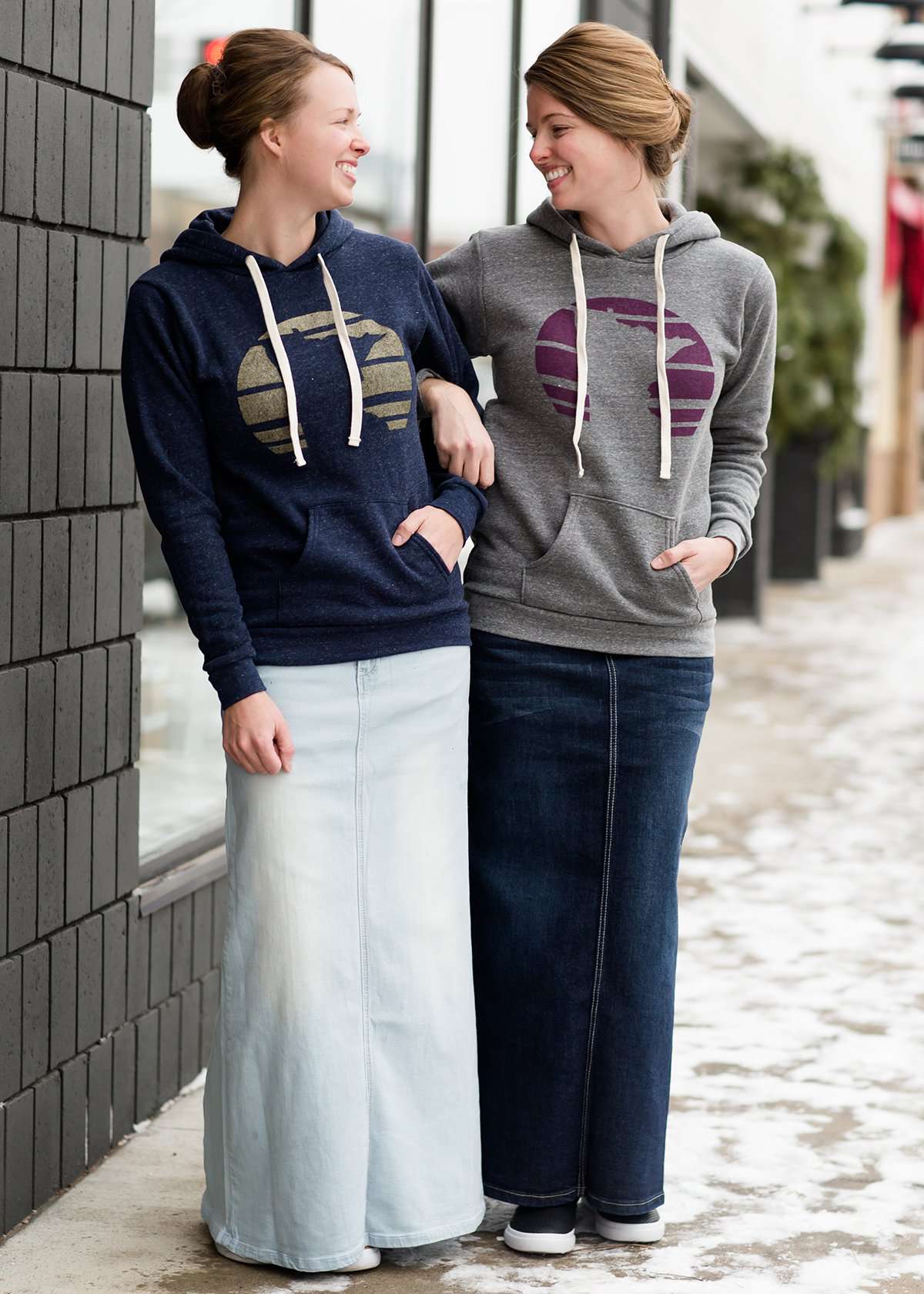 Triblend Minnesota hoodie on a young woman, the hoodie is navy with a gold MN emblem on front and gray with a purple MN emblem on front.