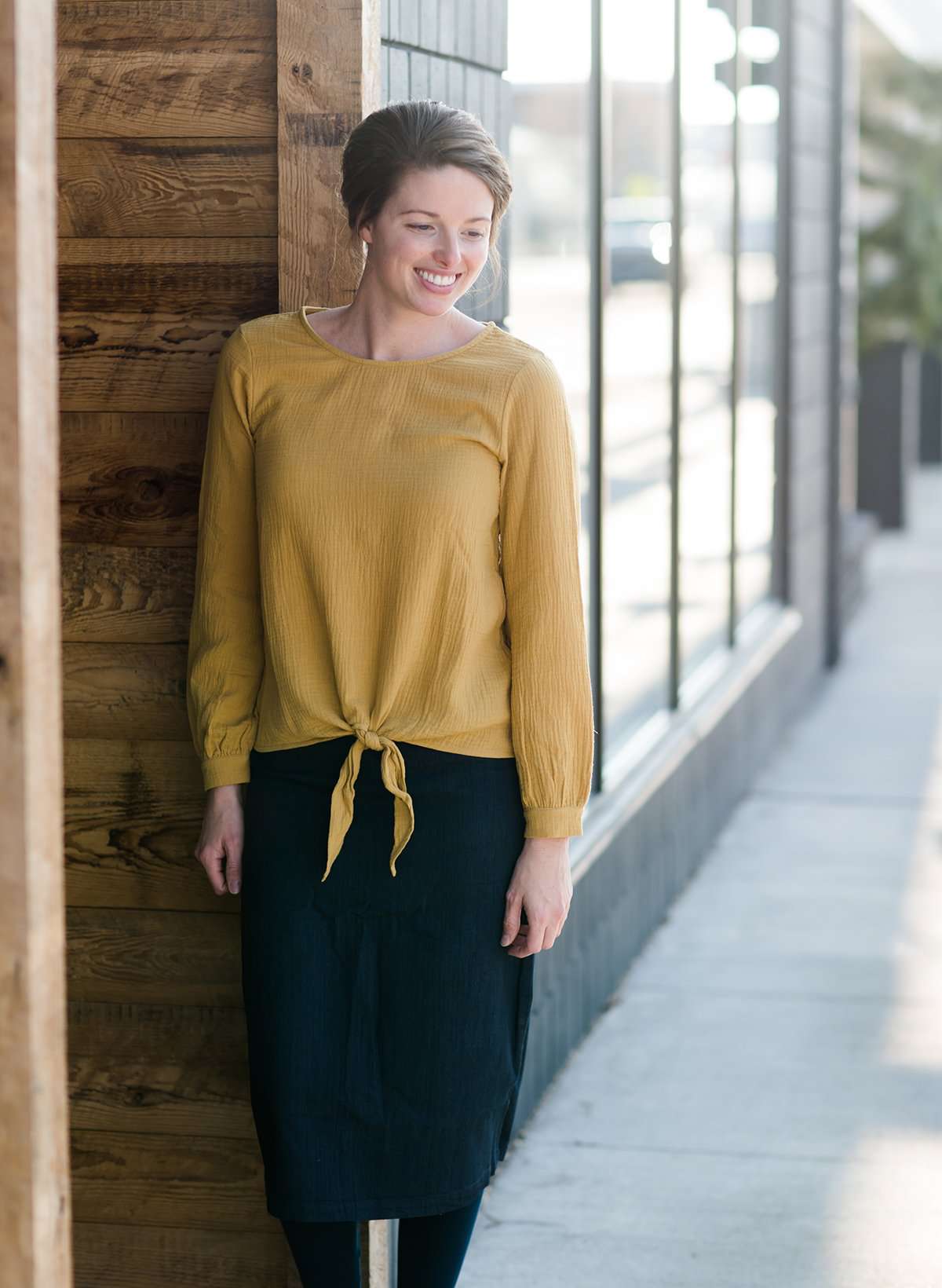 Woman wearing a mustard tie front top with back buttons
