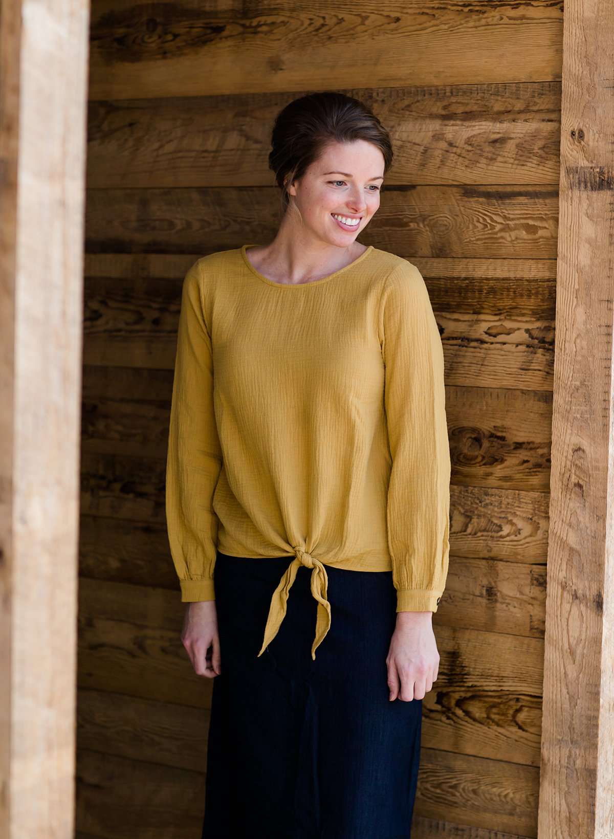 Woman wearing a mustard tie front top with back buttons