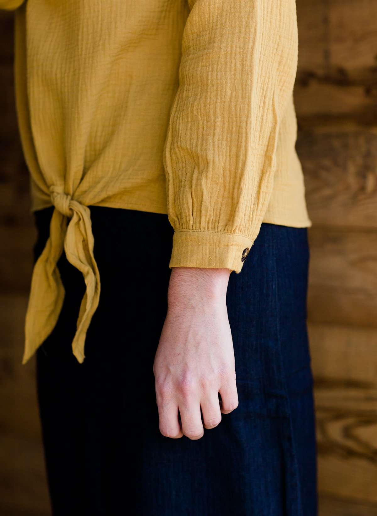 Woman wearing a mustard tie front top with back buttons