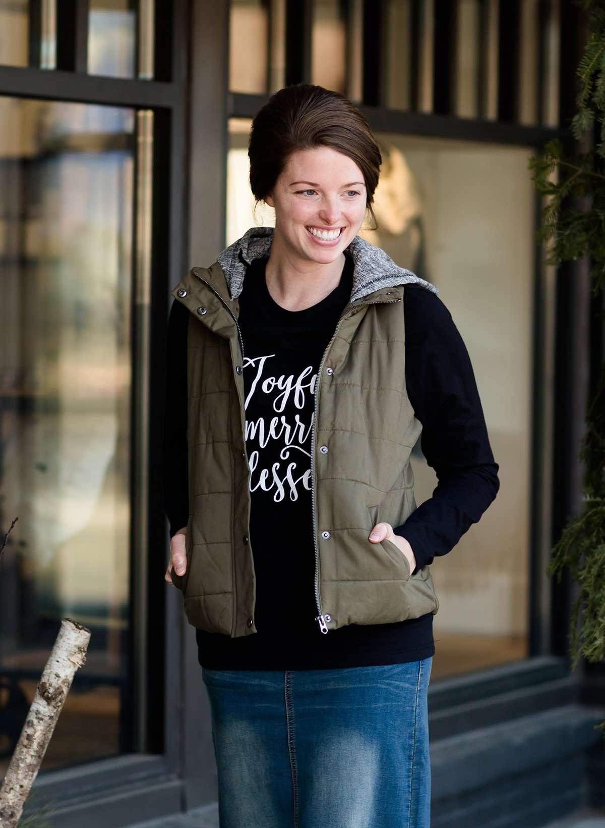 Woman standing out side of Inherit Clothing Company wearing a red and black, Joyful, Merry + Blessed Graphic Long Sleeve Tee.