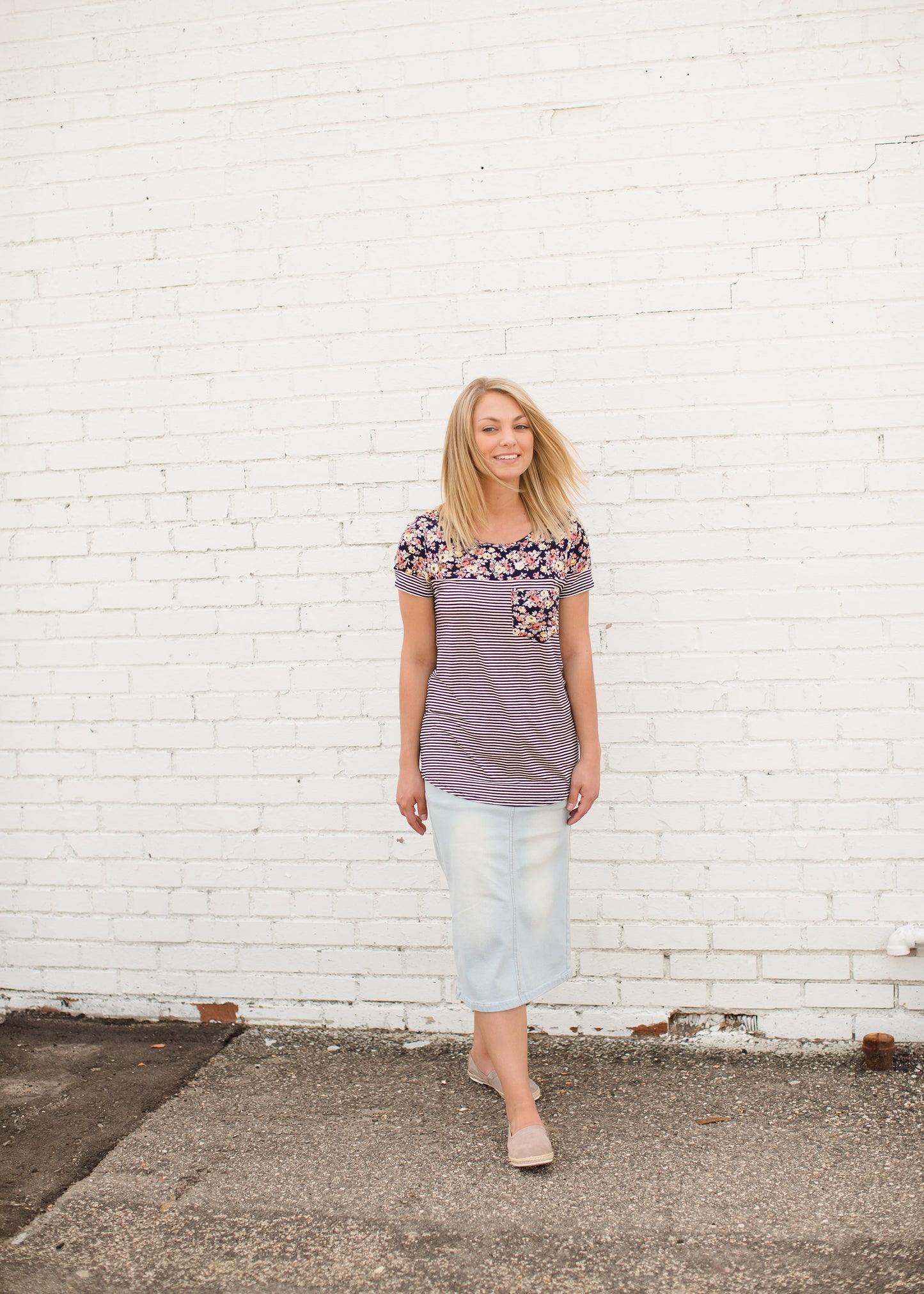 Young lady wearing a light denim below the knee jean skirt.