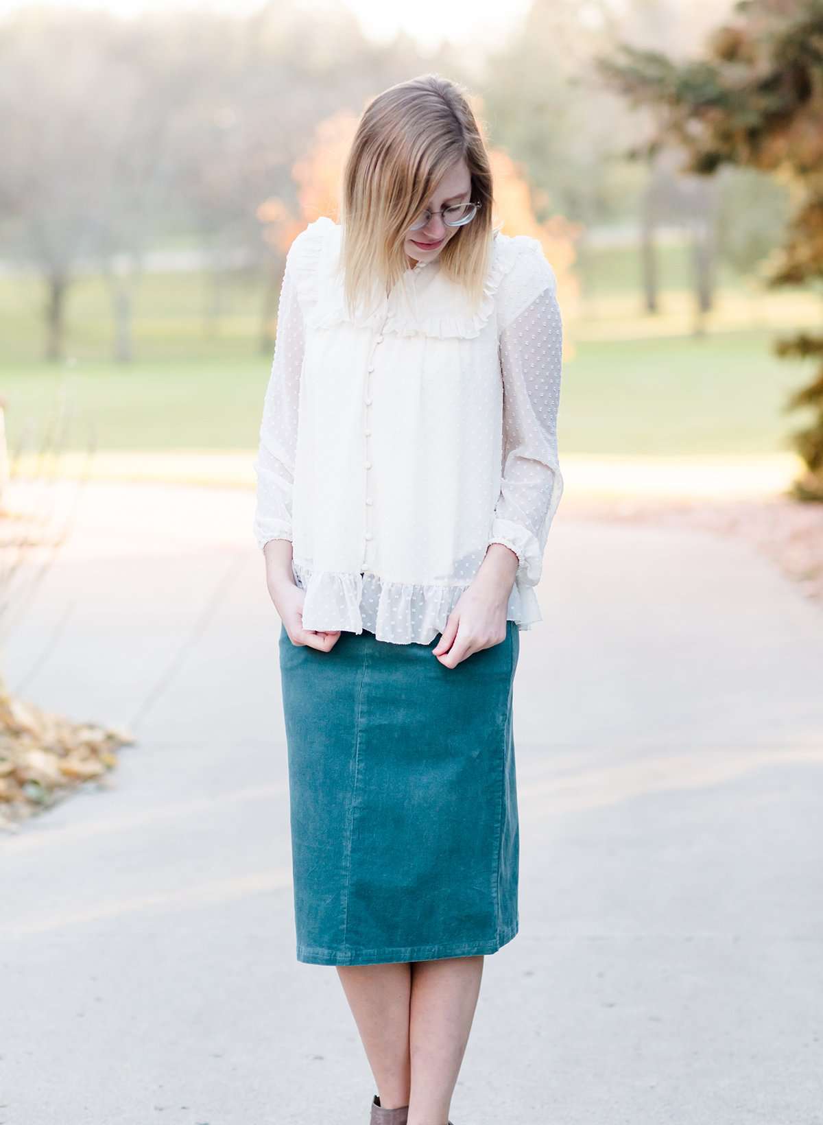 Young woman wearing a vintage inspired ruffle and layered cream colored blouse. This blouse features ruffles and ribbon details.