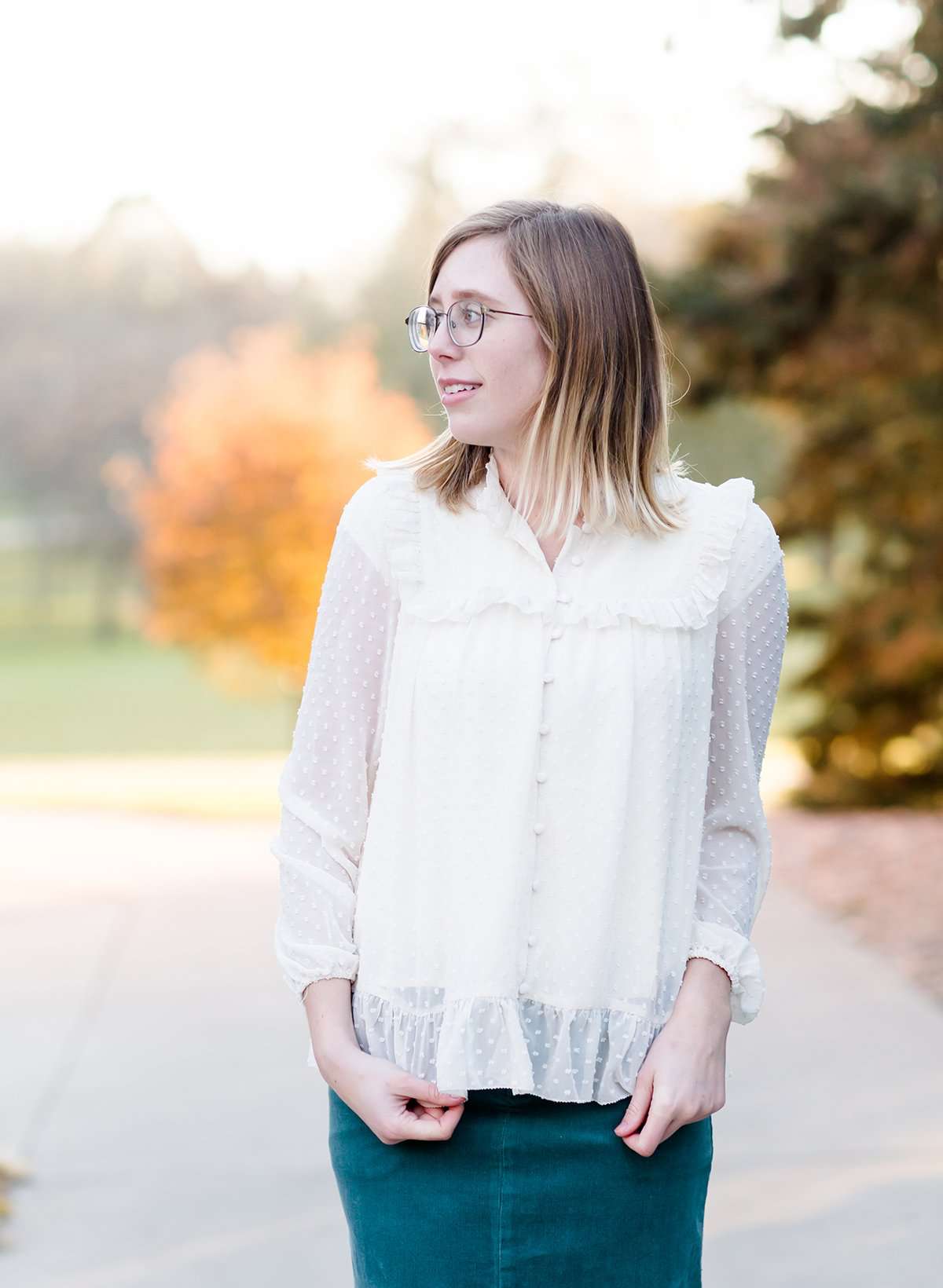 Young woman wearing a vintage inspired ruffle and layered cream colored blouse. This blouse features ruffles and ribbon details.