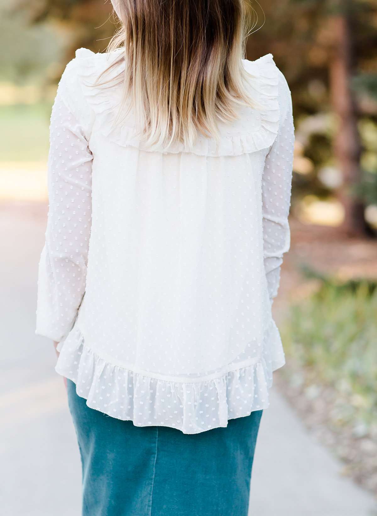 Young woman wearing a vintage inspired ruffle and layered cream colored blouse. This blouse features ruffles and ribbon details.