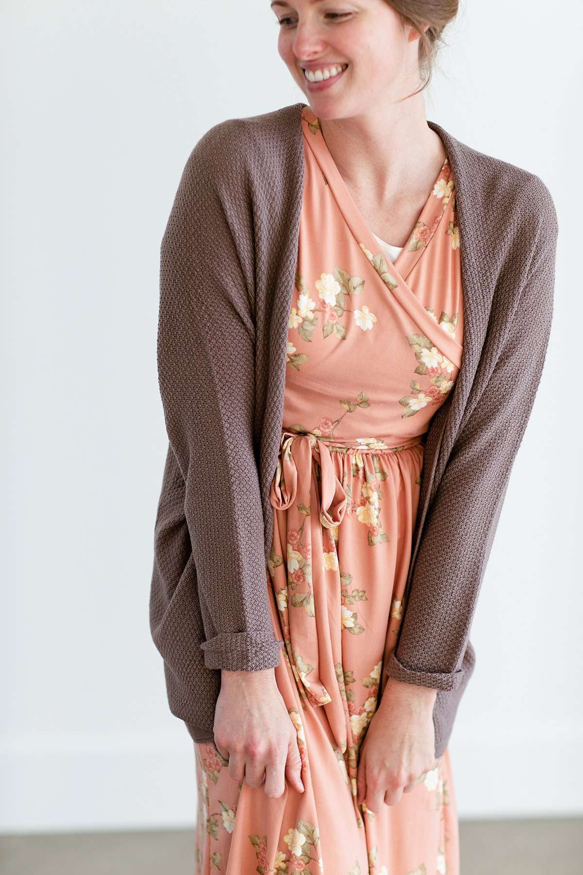Woman wearing a lightweight knit cardigan in navy, taupe or cream.