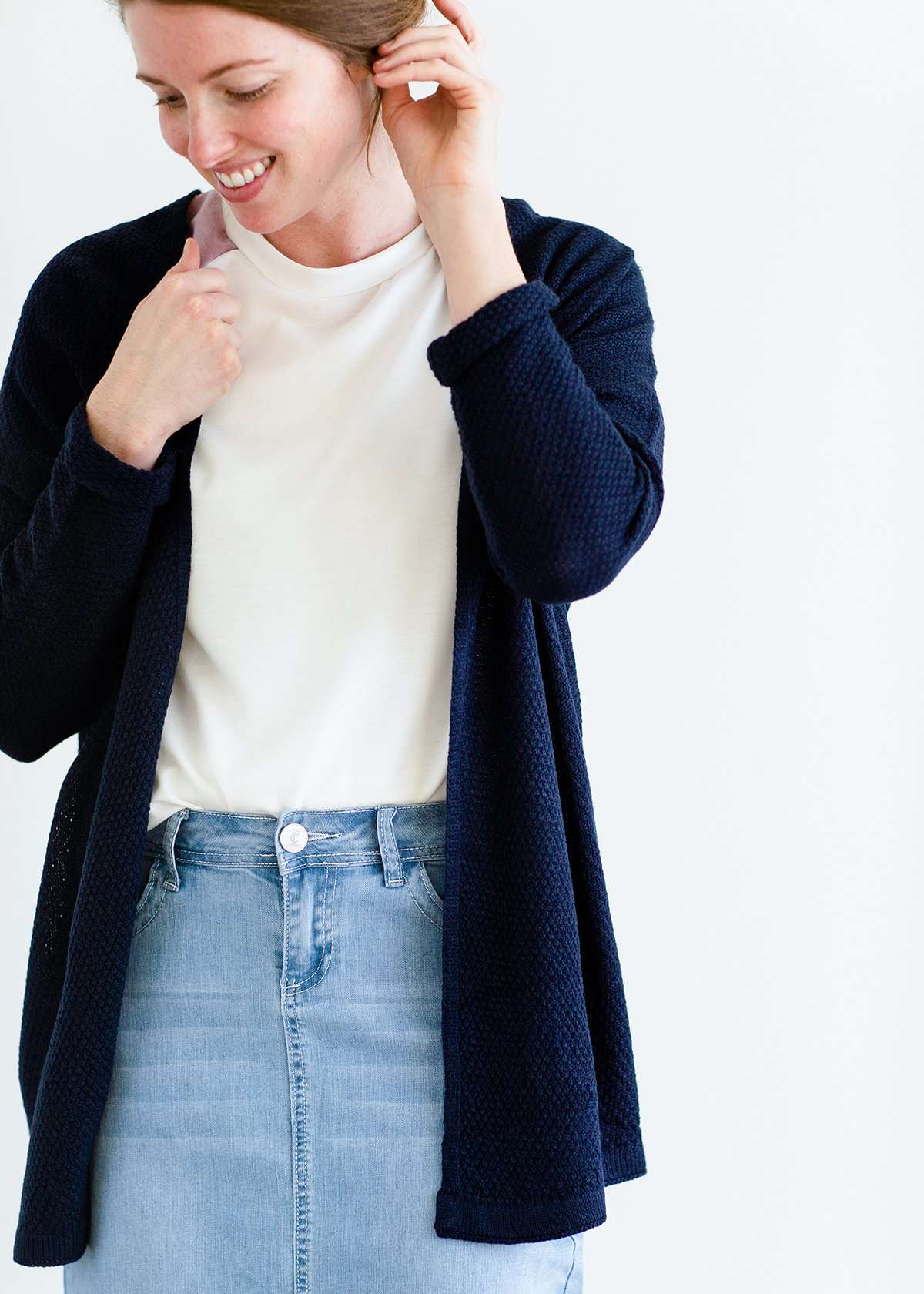 Woman wearing a lightweight knit cardigan in navy, taupe or cream.