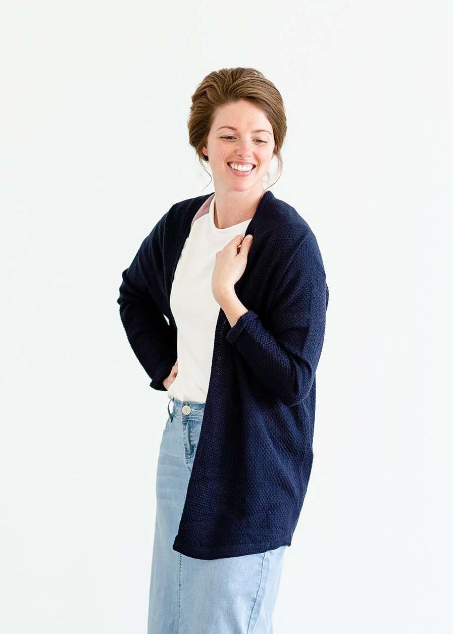 Woman wearing a lightweight knit cardigan in navy, taupe or cream.