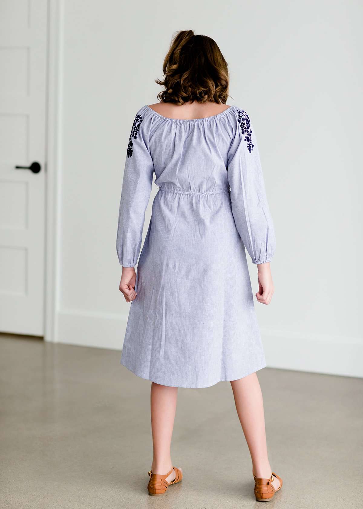 Tween wearing a navy boho pin stripe peasant dress with a self tie belt
