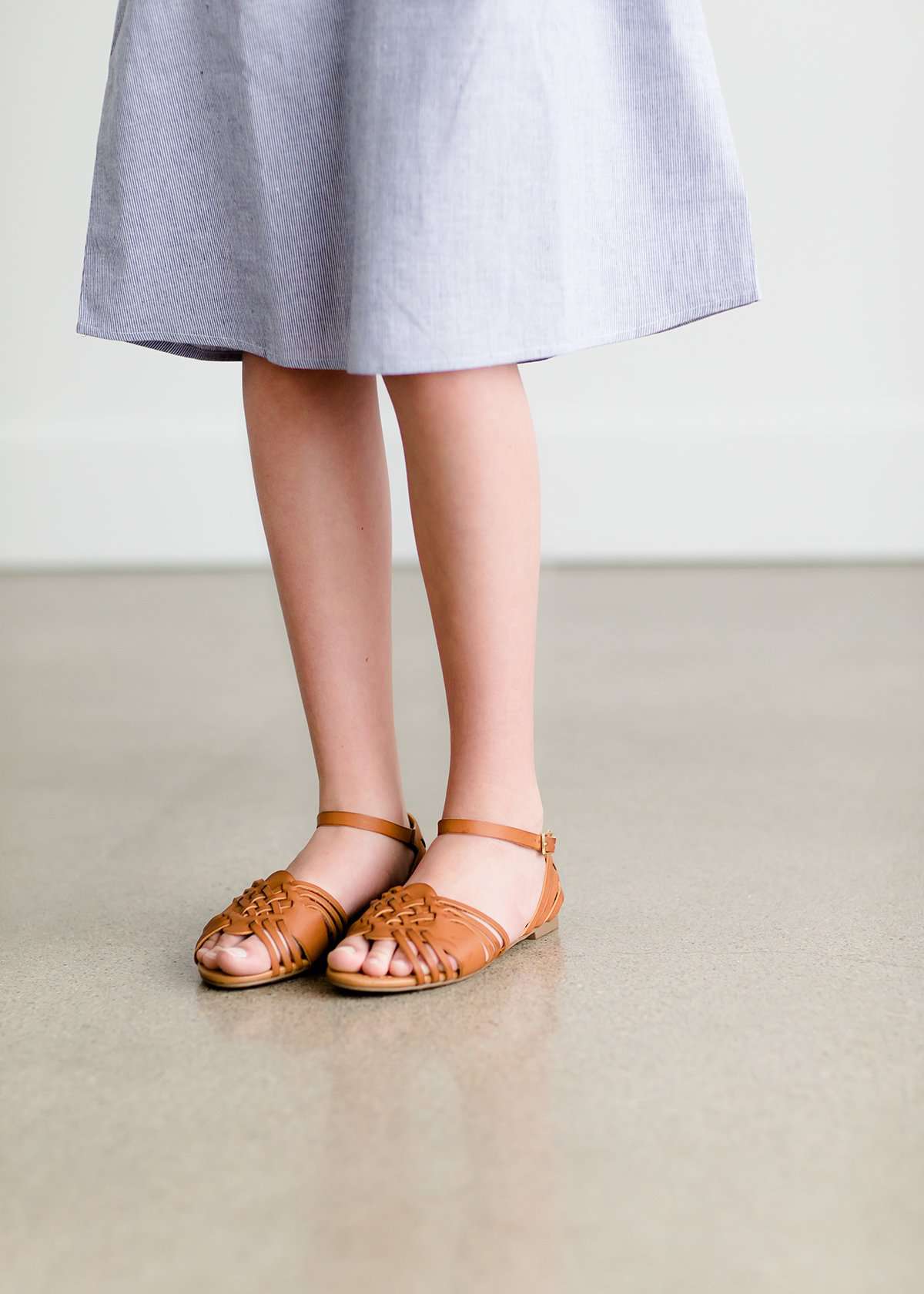Tween wearing a navy boho pin stripe peasant dress with a self tie belt