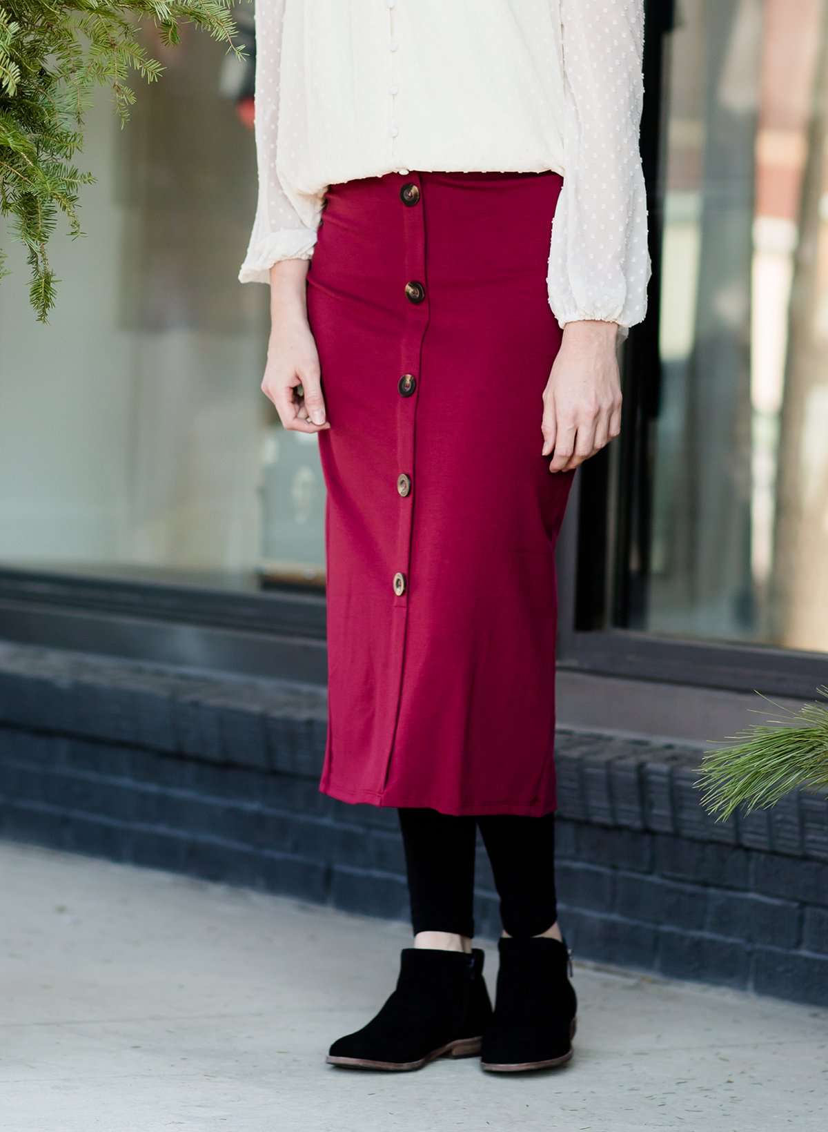 Modest below the knee wine colored skirt. This skirt has faux buttons and is paired with a white blouse and black boots.